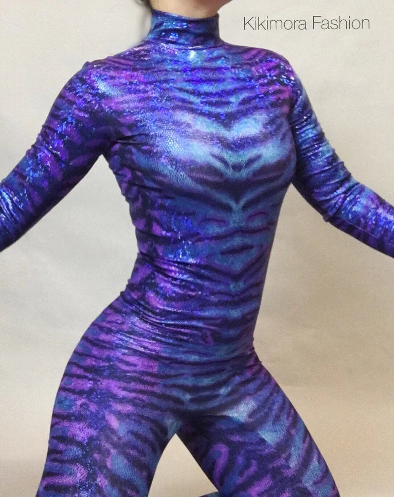 Person wearing a shiny, purple and blue tiger-print bodysuit with arms slightly outstretched.