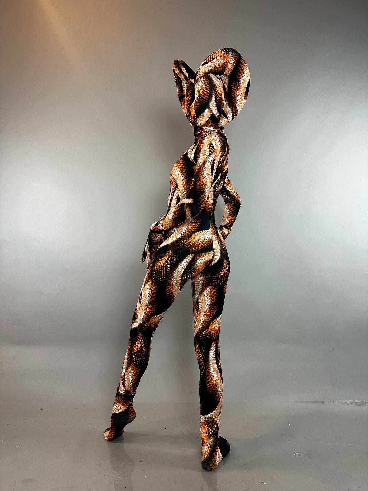 Person wearing a Brown Cobra Costume in a brown and black snake-print bodysuit with a cobra-shaped hood.
