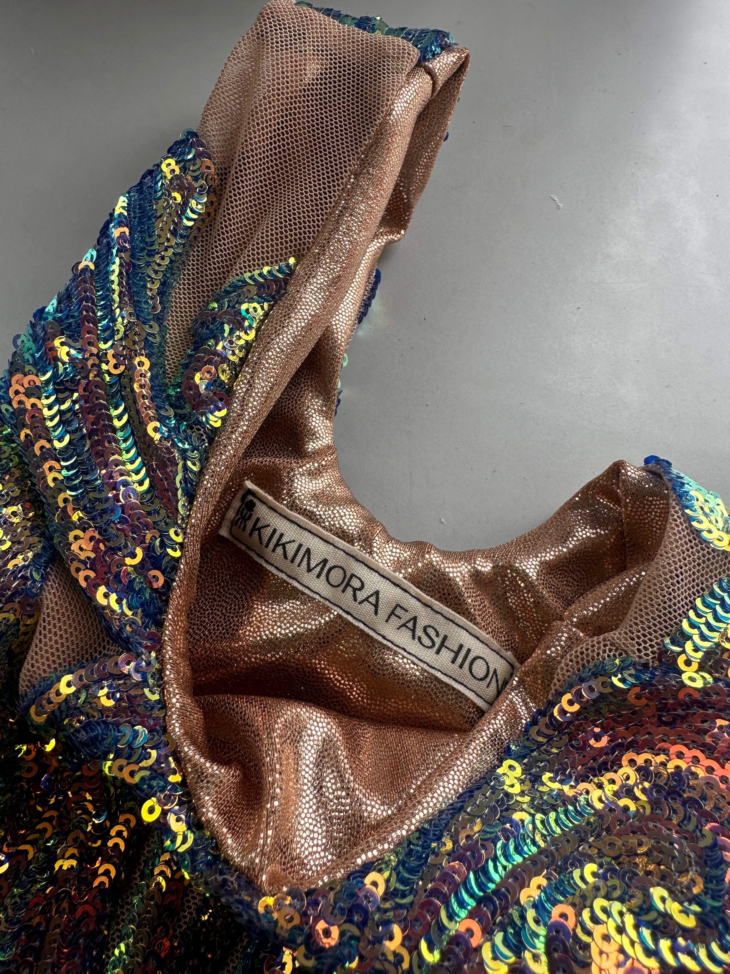 The Handcrafted reversible sequin mini tote, a sustainable fashion accessory, features sparkly, metallic-lined fabric inspired by KIKIMORA FASHIONās upcycled Miami bags collection.