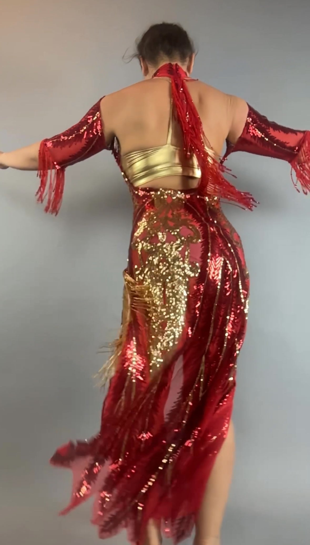 Person wearing the bearded French accessories Sequin Sheer Dress, featuring a backless design and beaded fringe accessories, arms outstretched and seen from behind.
