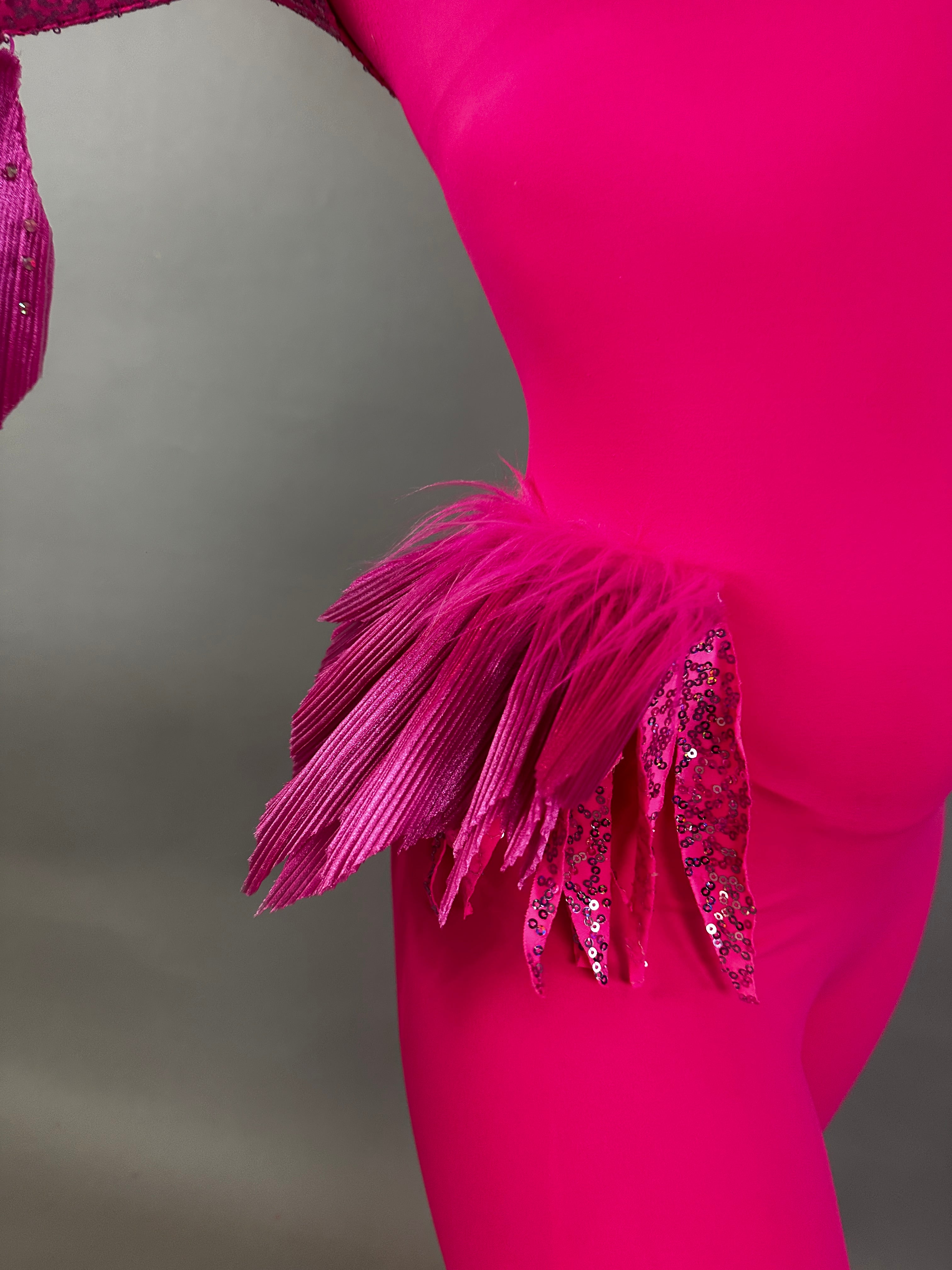Model wearing the Pink Bird Full Costume for aerial and dancers, featuring pleated and sequined feather-like hip details, shown against a plain background.