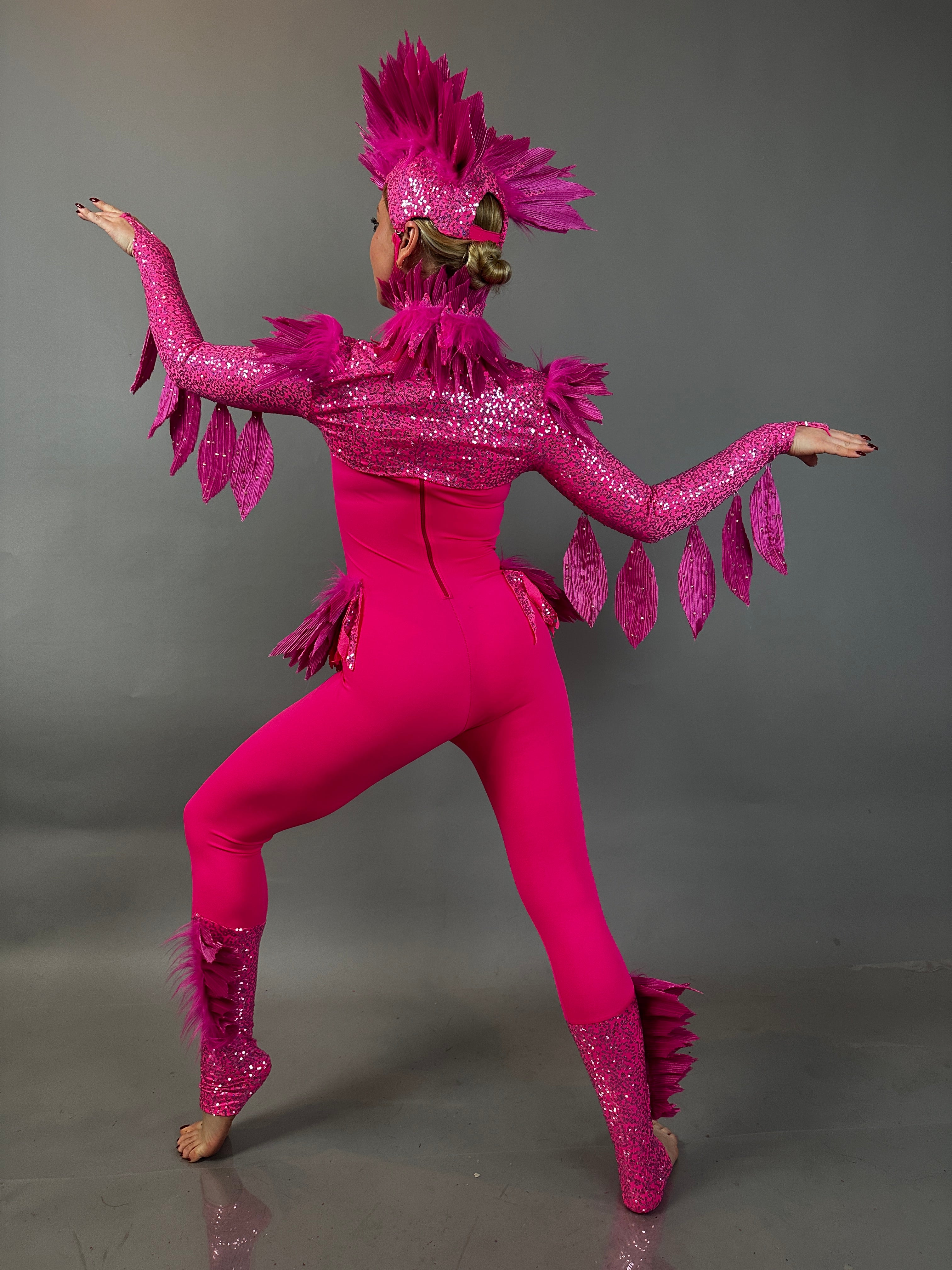A performer in the Pink bird full costume for aerial and dancers poses with arms raised against a gray background, showcasing the energetic style of this stage-ready outfit.
