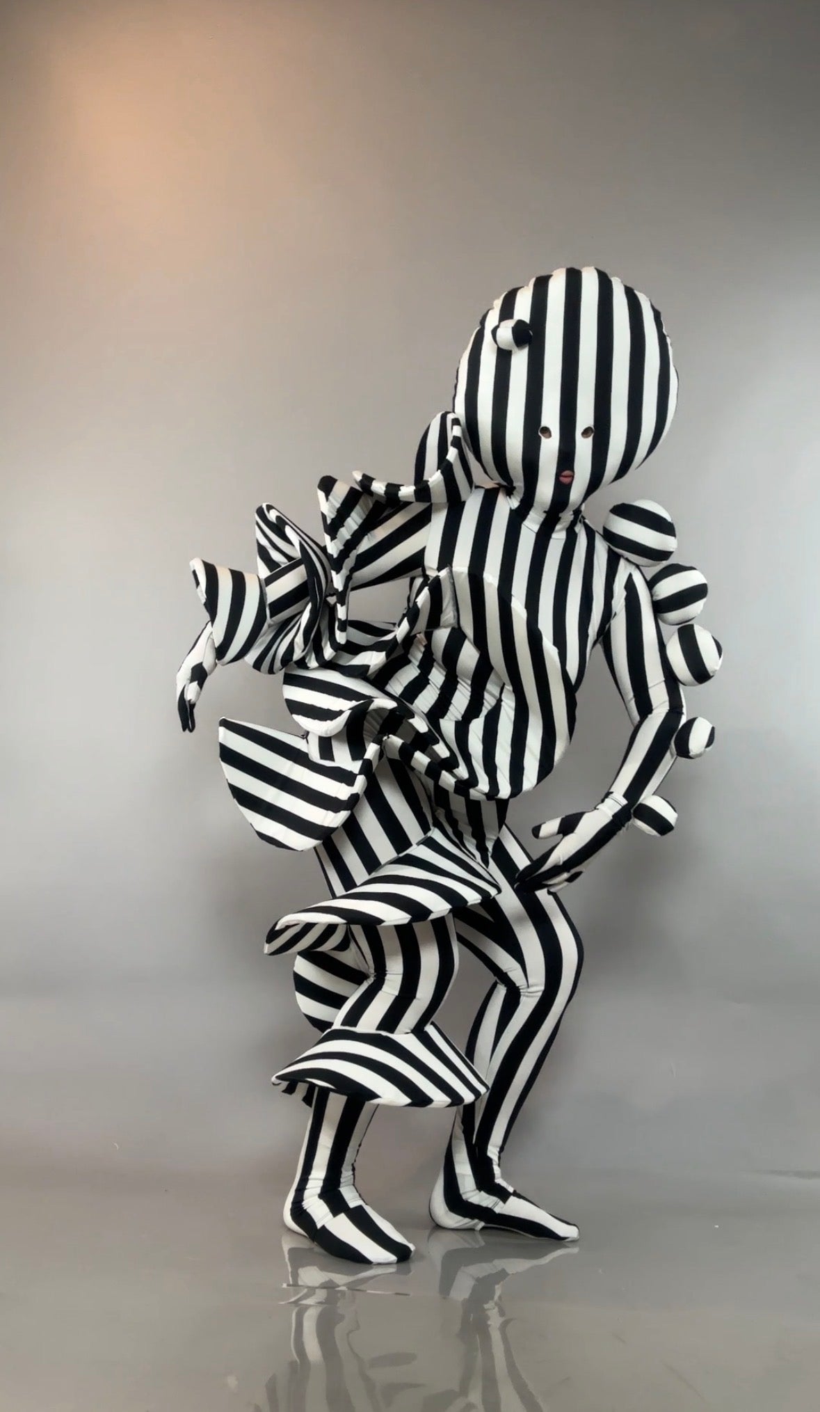 Black and White Striped Creature Costume with sculptural, ruffled, and spherical parts in a black-and-white jumpsuit.