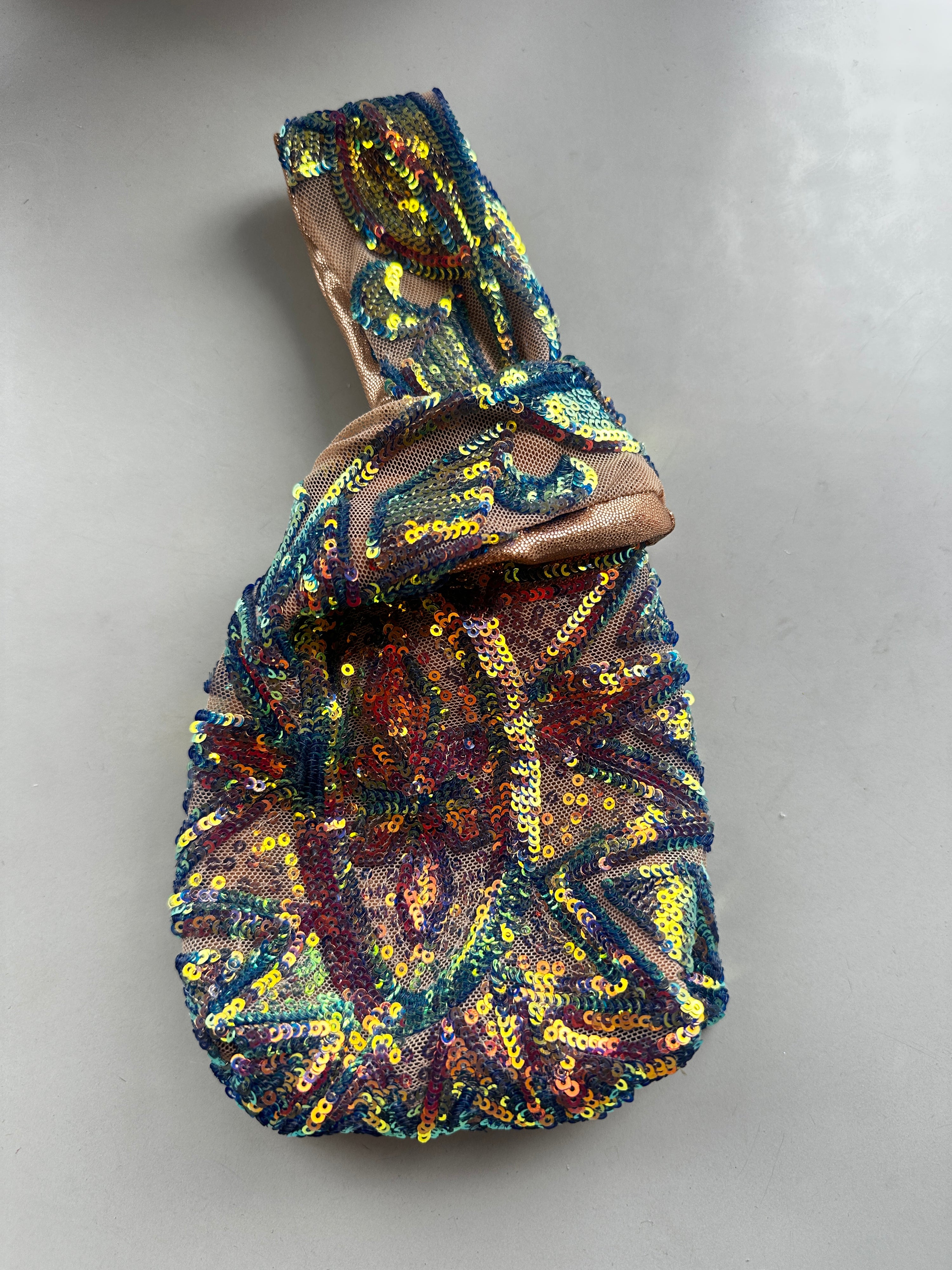 Handcrafted reversible sequin mini toteāa colorful, sustainable fashion accessory with a looped handleālies on a light gray surface.