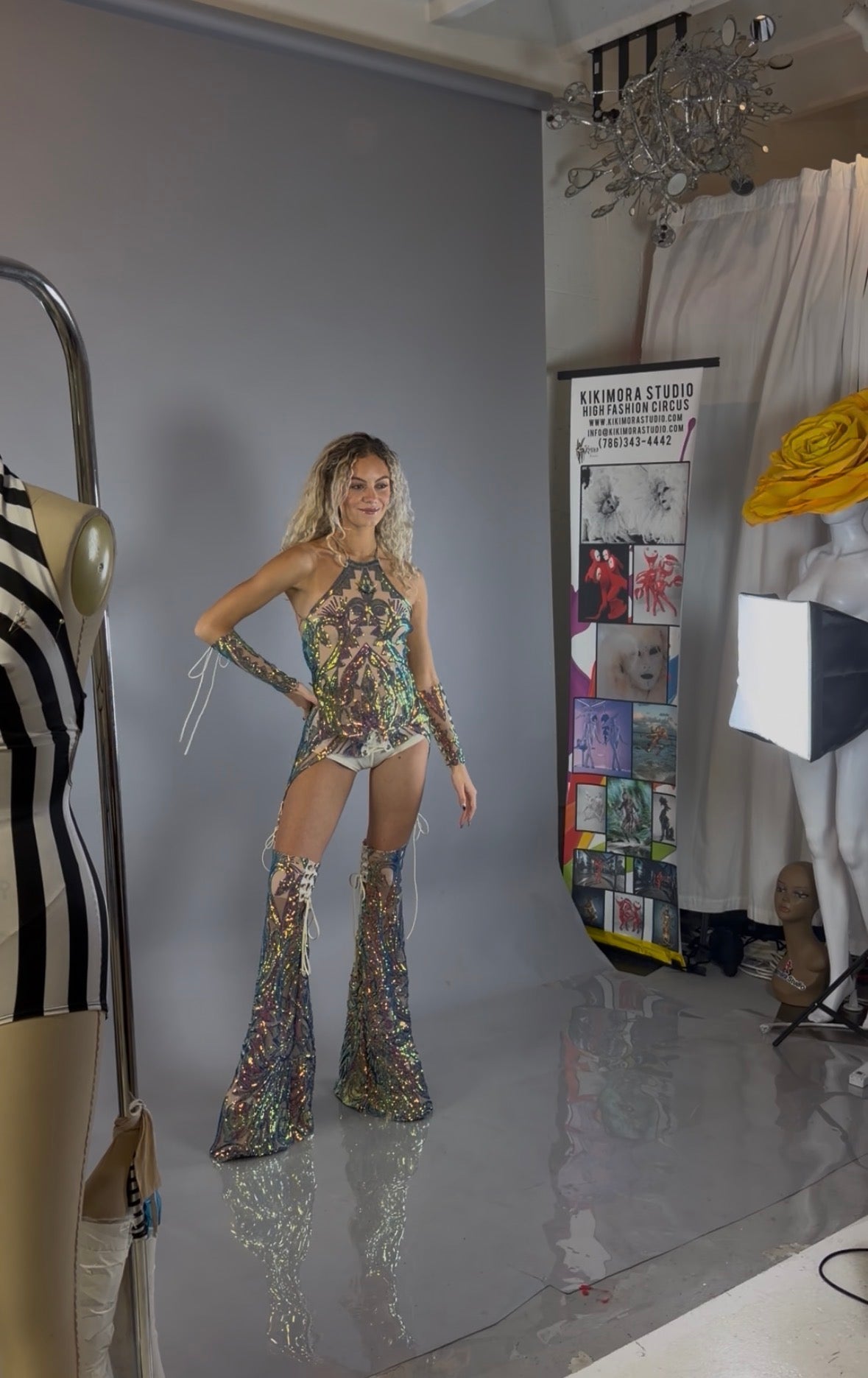 A model showcases a stunning custom dancewear look in a vibrant sequins costume set, featuring chaps pants and a laced top designed as a festival costume, photographed in a fashion studio.