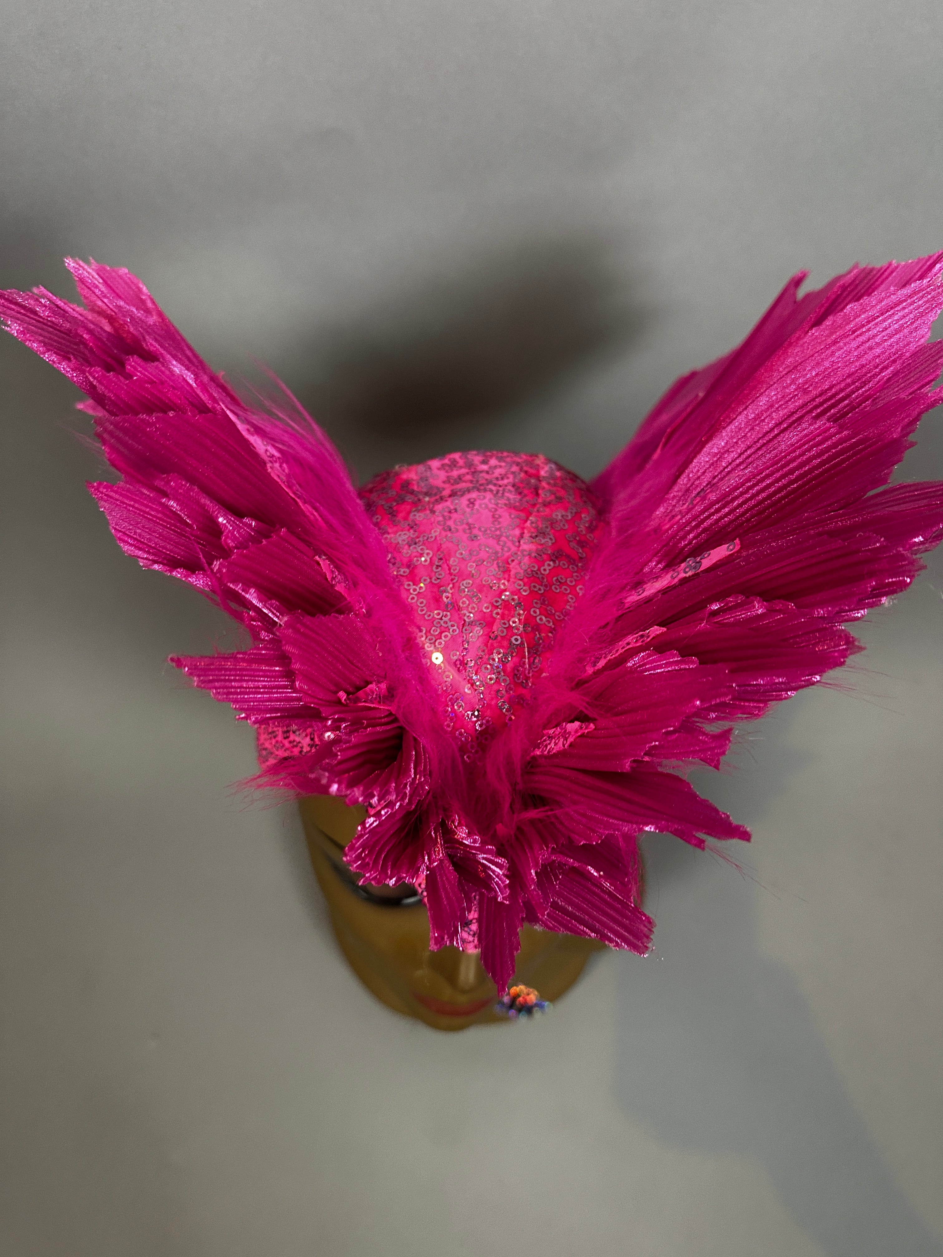 The Pink Bird Headpiece is a vibrant fairy hat with large, feather-like wings on each side, perfect for aerialists or theatrical costumes, shown here against a gray background.