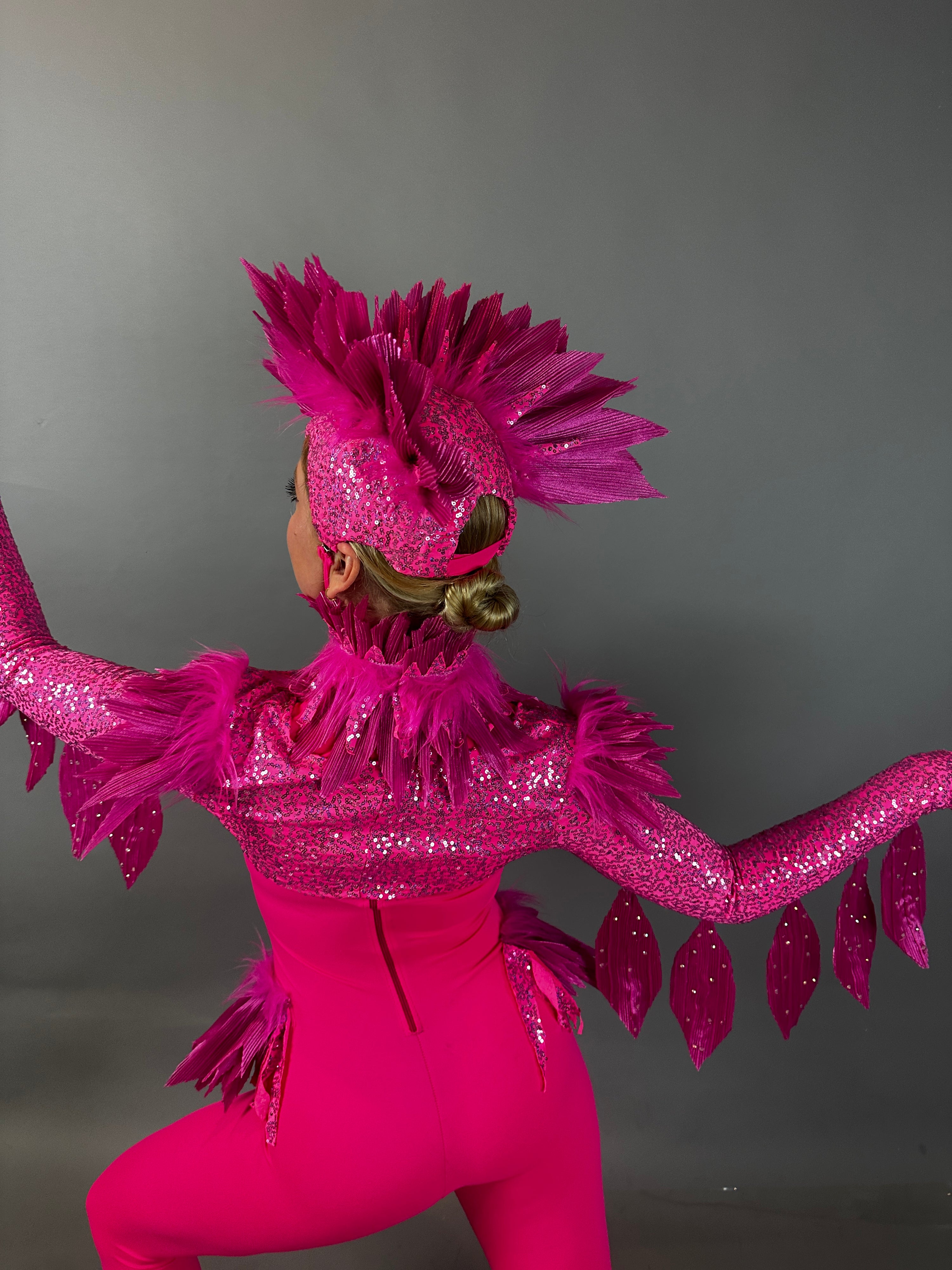 Model showcases the Pink Bird Full Costume for aerialists and dancers, striking a dynamic pose with arms outstretched against a neutral gray backdrop—perfect for captivating stage shows.
