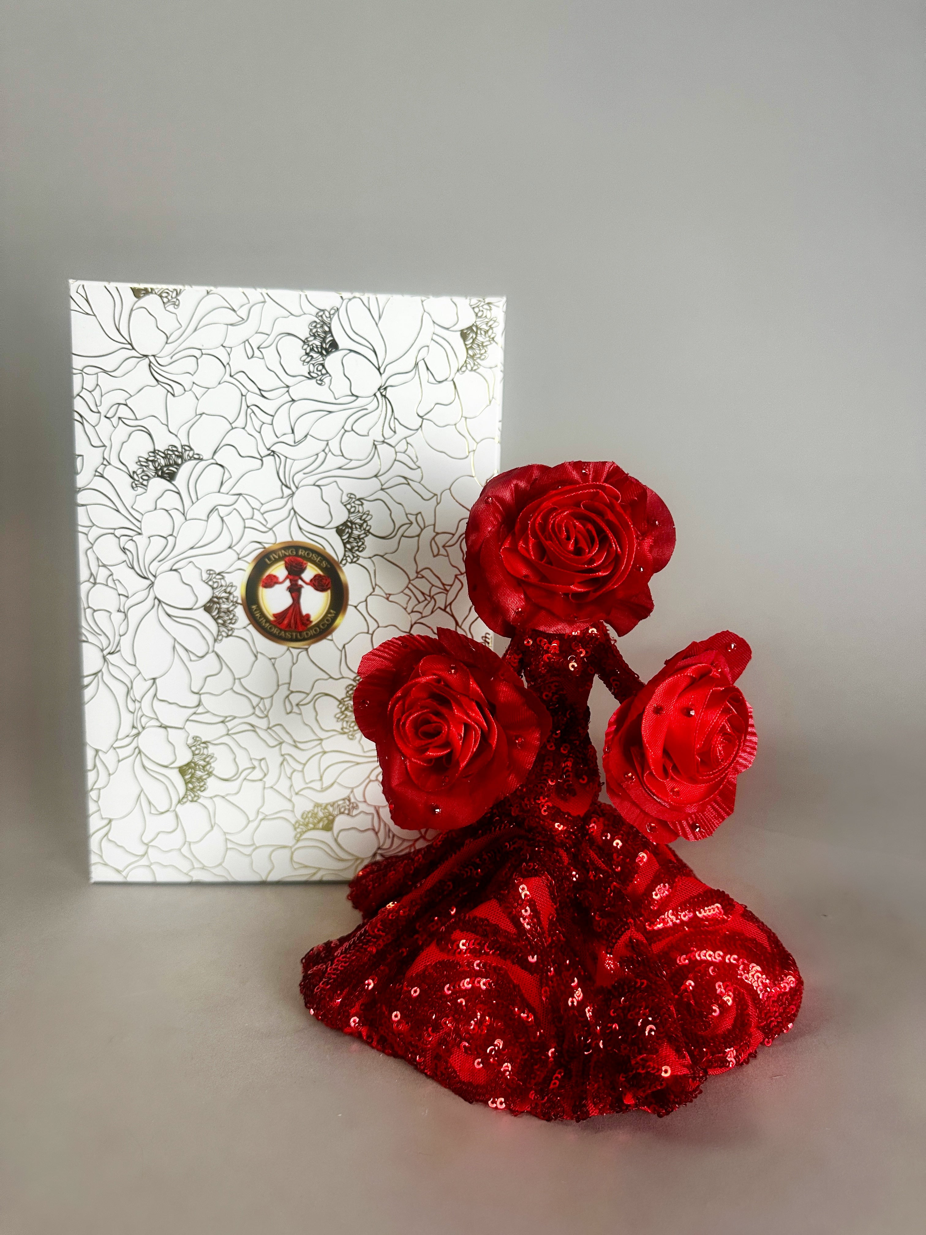 The Mini Living Rose sculpture by Kikimora Studio is a handcrafted doll ornament shaped like a red rose dress, displayed before a floral white box for a magical art touch.