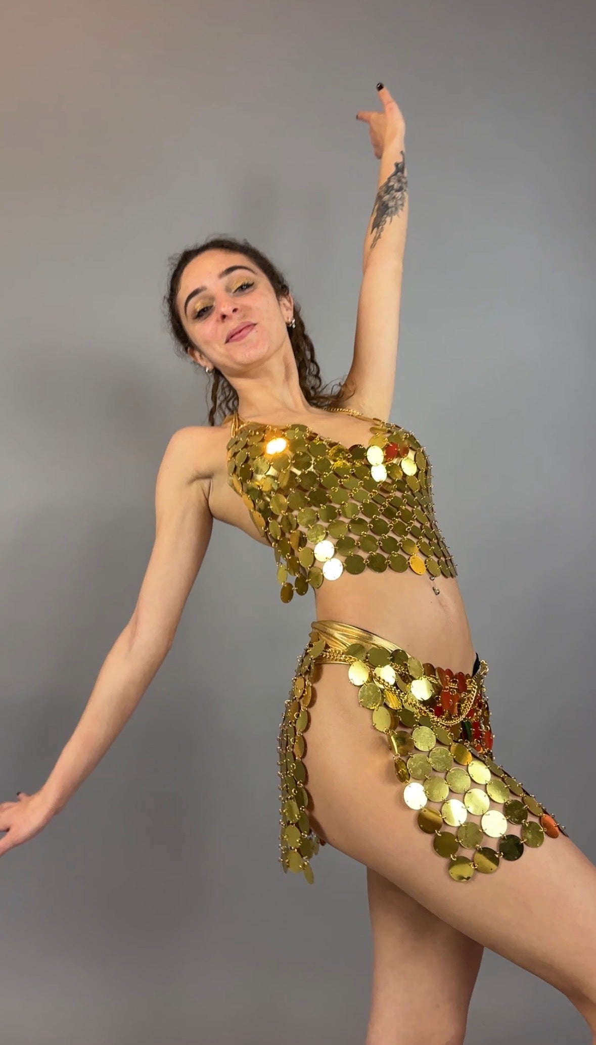 A woman poses in the Gold Chain Two-Piece Set for Performers, featuring a supportive crop top costume, perfect for stage performances, against a simple gray background.