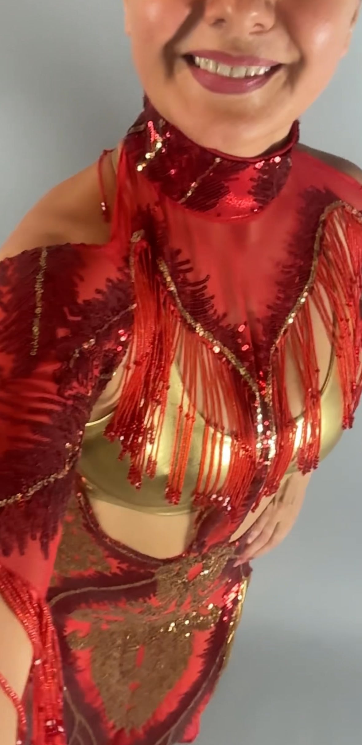 Smiling woman in the bearded French accessories Sequin Sheer Dress—red, backless, with beaded fringe—captured from above.