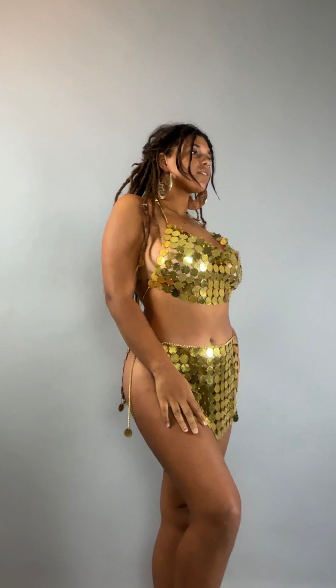 A woman models the Gold Chain Two-Piece Set for Performers costume, posing confidently against a plain light gray background.