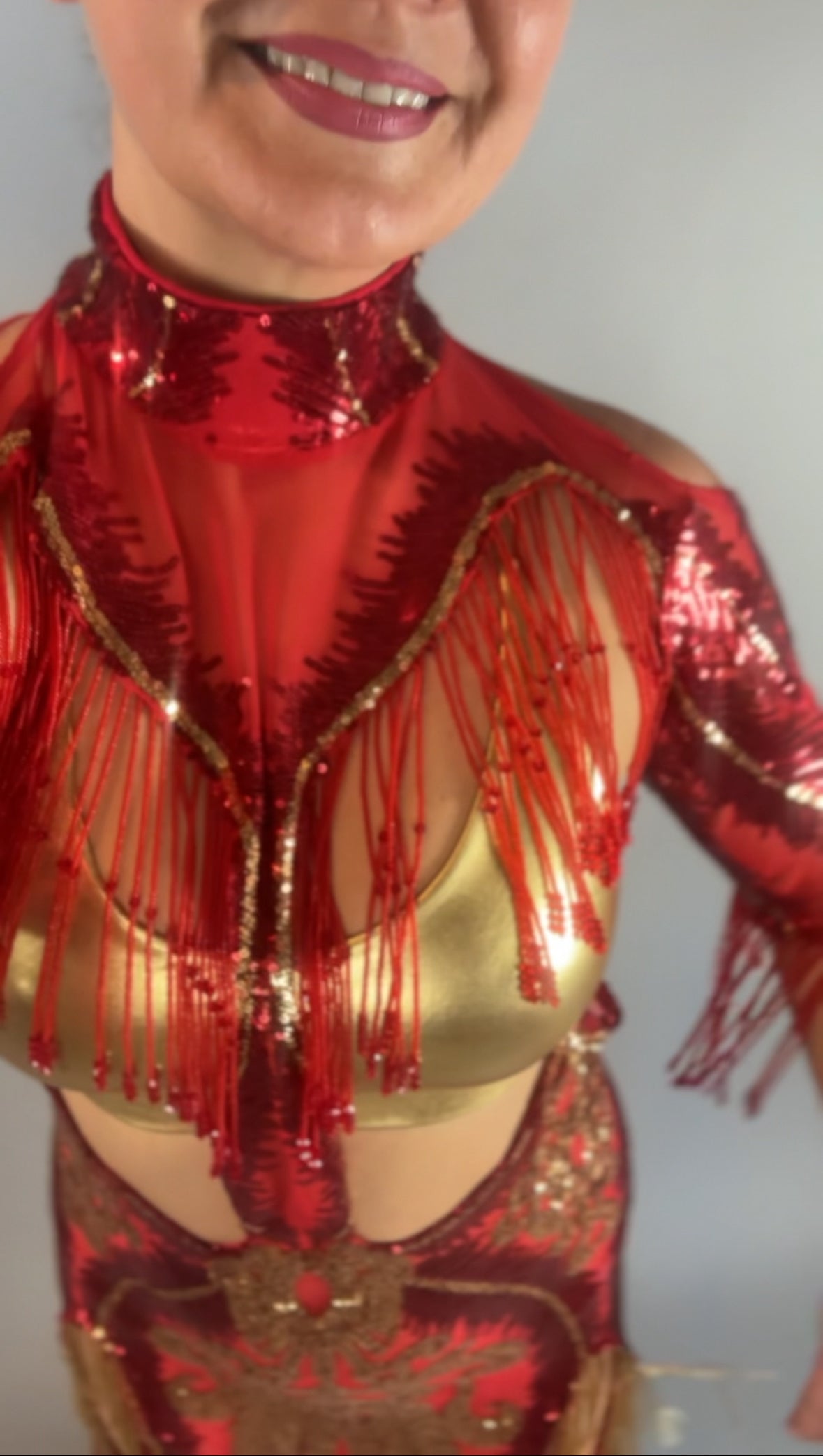 Woman smiling in the bearded French accessories Sequin Sheer Dress, a backless design with beaded fringe details, shown from shoulders to waist.