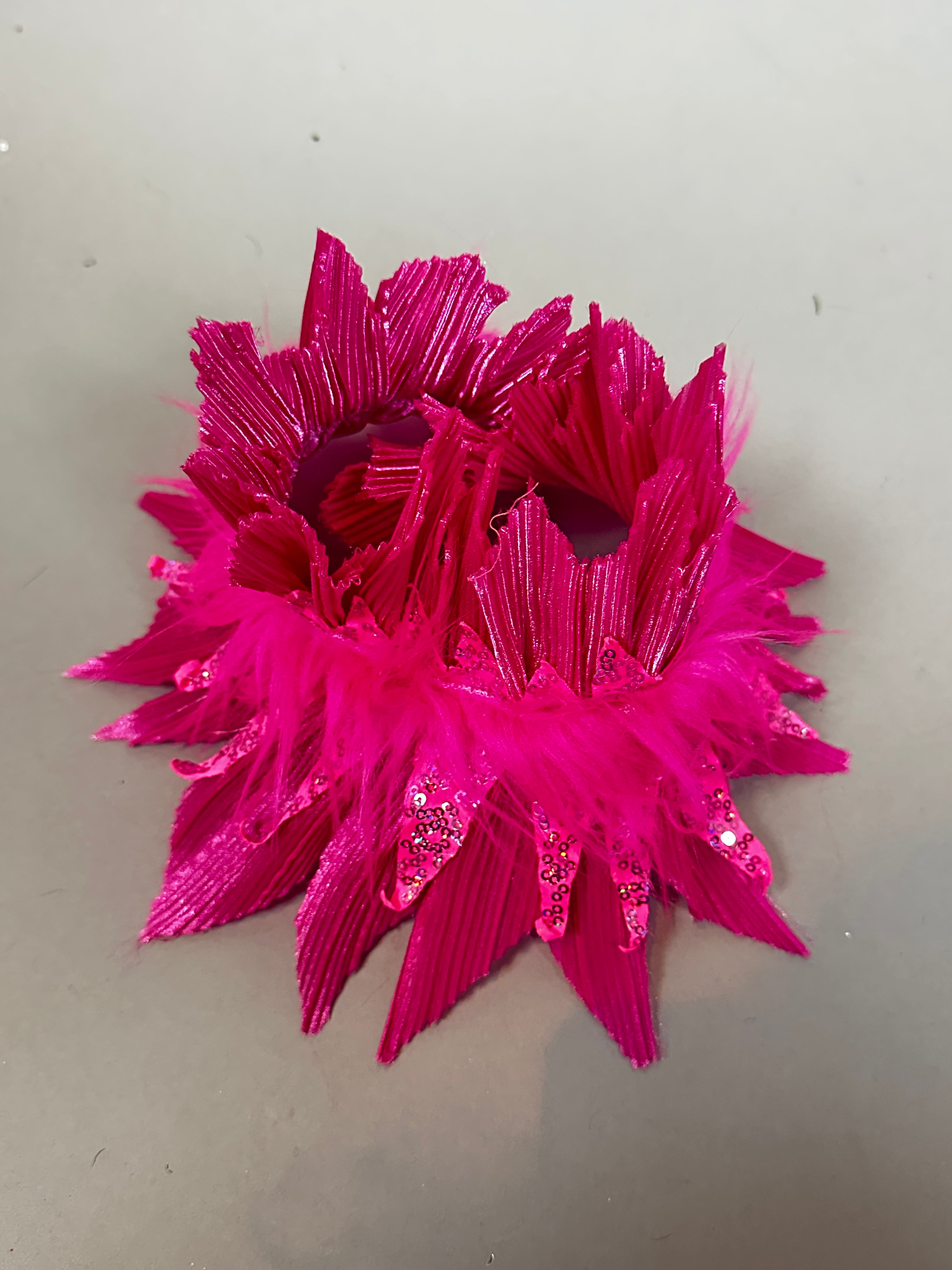 The Pink bird full costume for aerial gymnastics, dancers, and TV productions features bright pink, feathery, and sparkly decorative cuffs or accessories displayed on a plain gray surface.