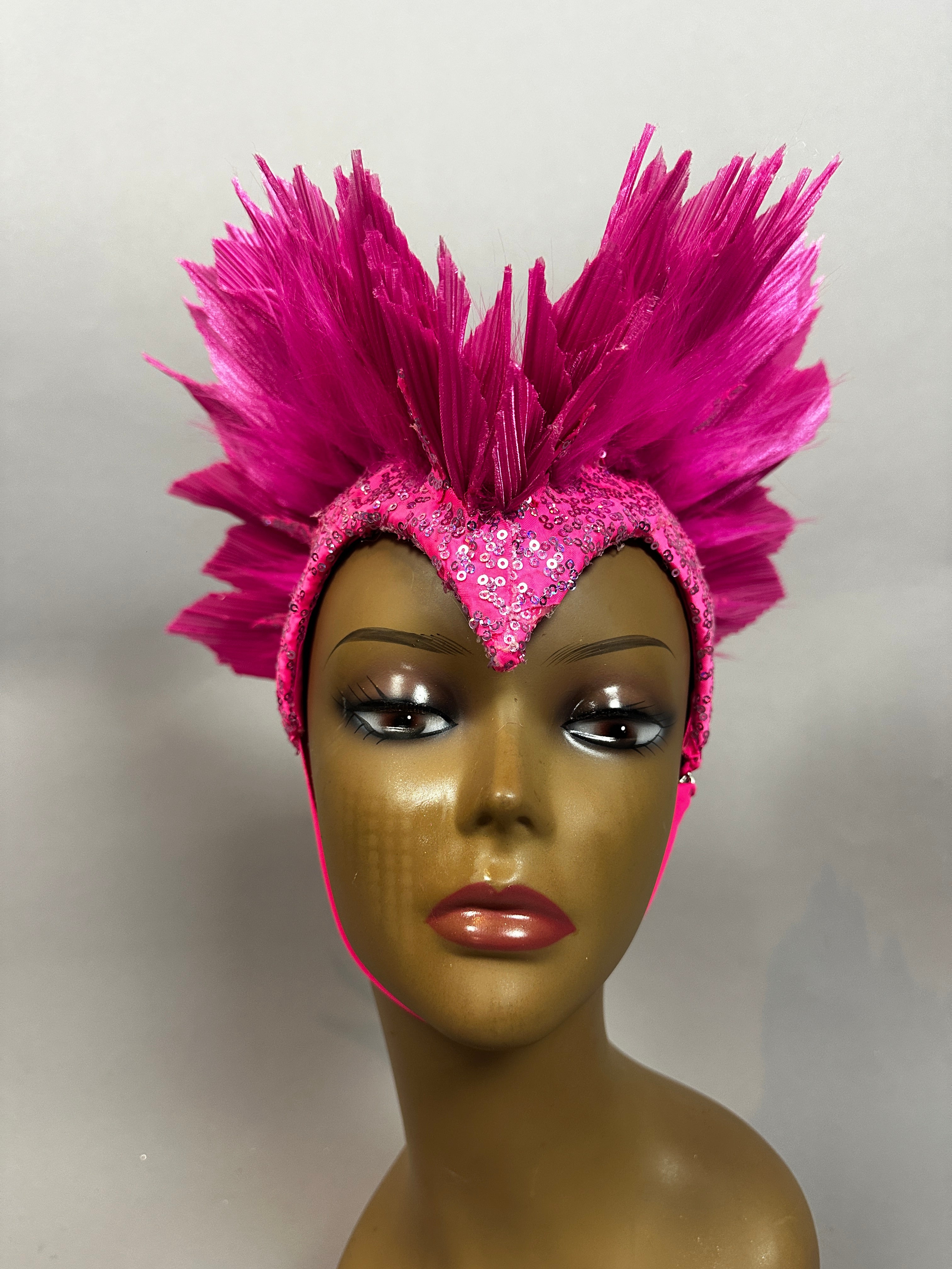 Mannequin head displays the Pink Bird Headpiece—a fairy hat and theatrical headwear for aerialists—featuring bright pink feathers and sequins in a dramatic fan shape, reminiscent of butterfly wings.