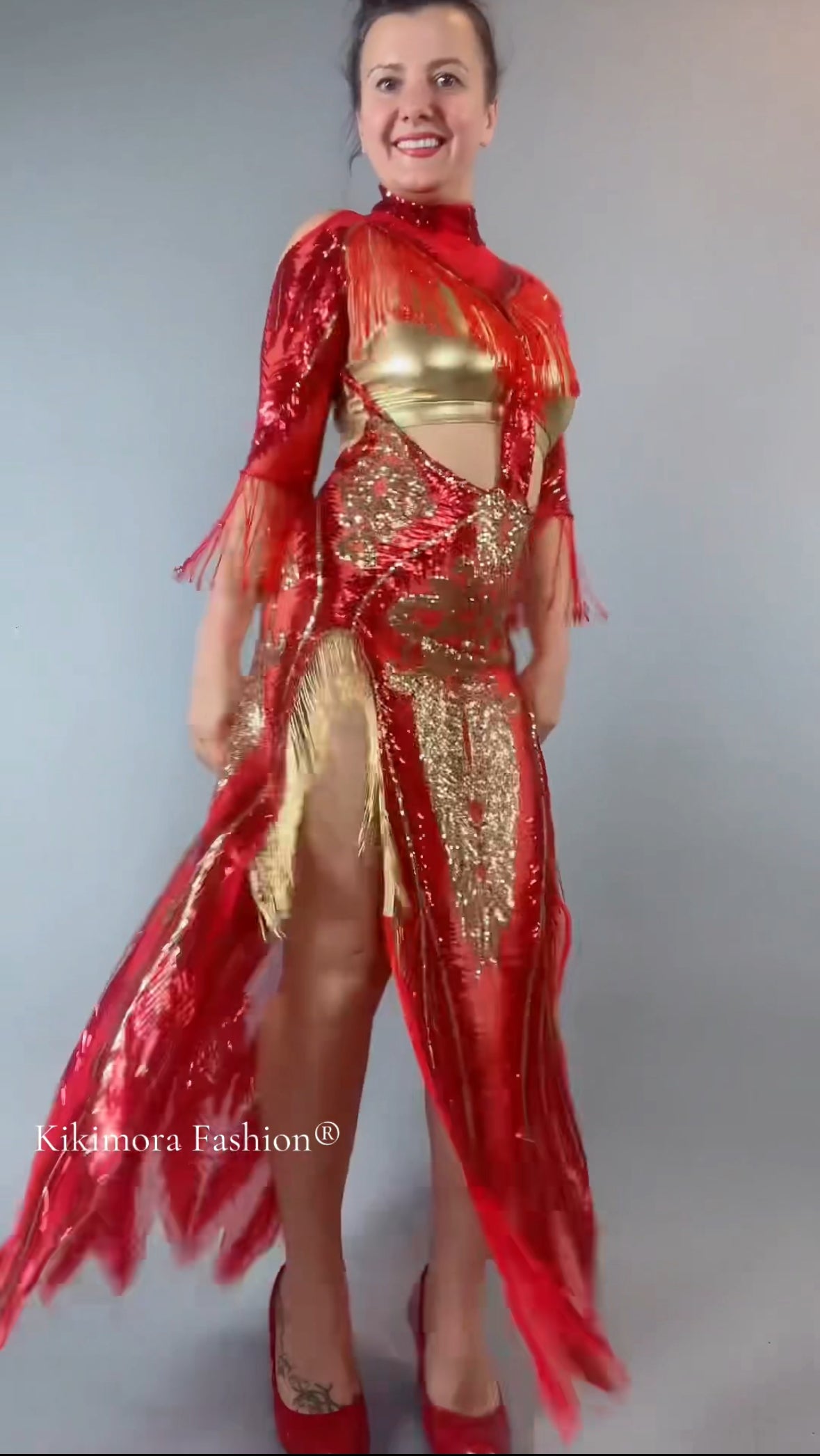 Smiling woman in a bearded French accessories Sequin Sheer Dress, backless with beaded fringe accessories, standing against a gray background.