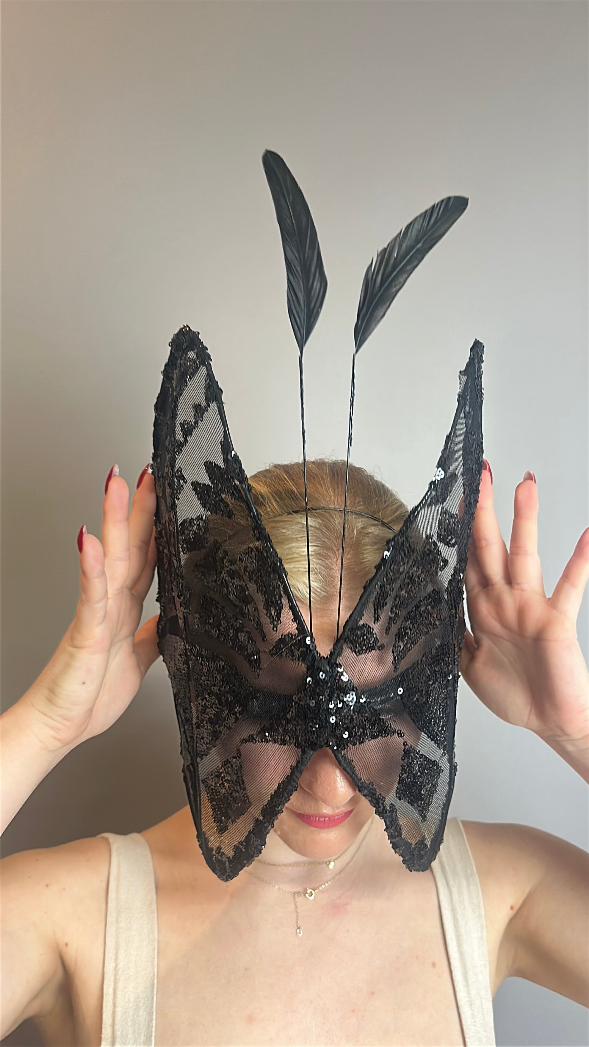 Person wearing a Butterfly Headpiece—an open-face black lace hat with festive holiday costume accents—hands raised near the accessory.