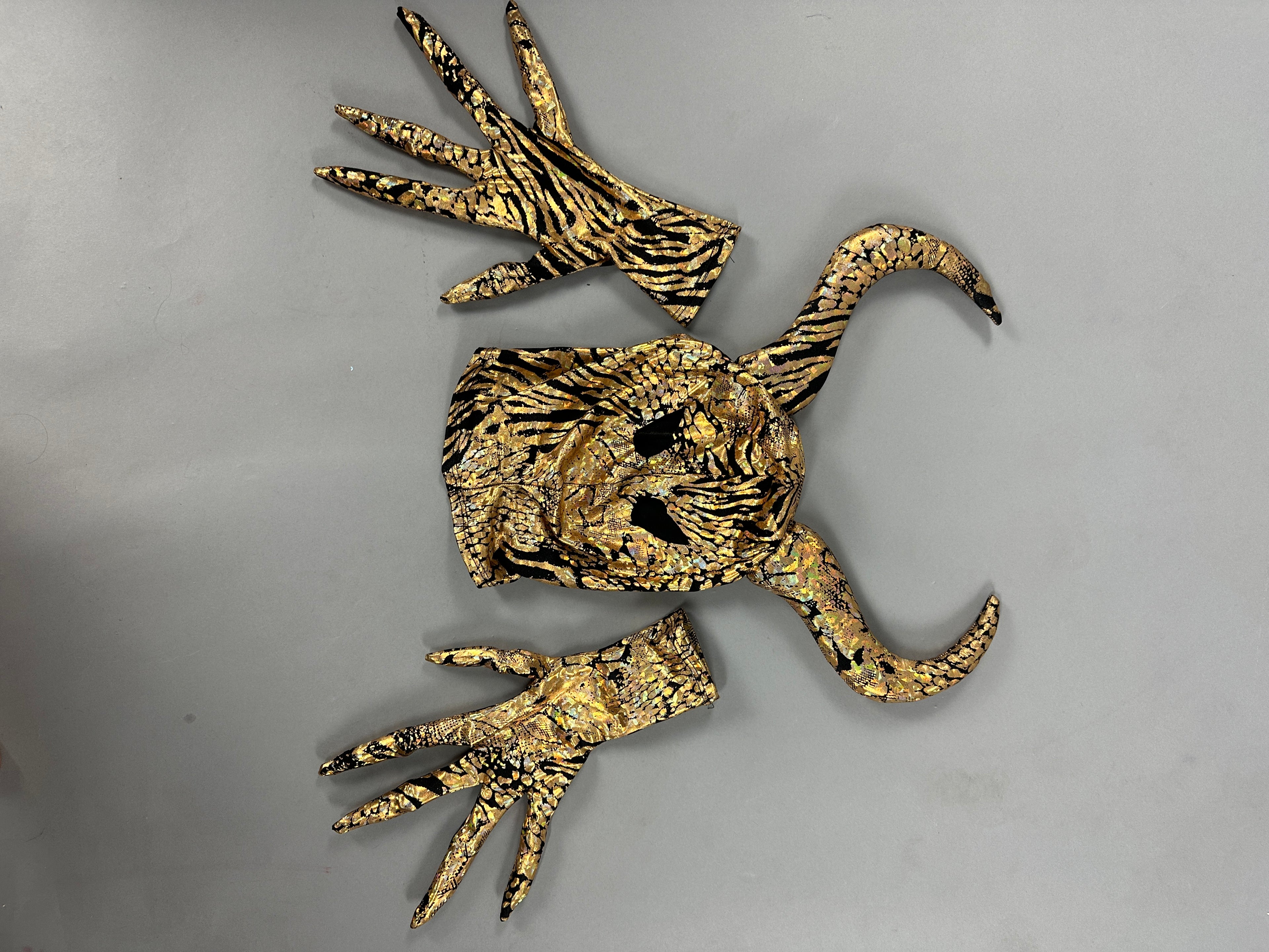 The Gold & Black Gazelle Creature Costume features a majestic gazelle-like mask with horns, full-sleeve catsuit, matching gloves, and socks on a gray background.