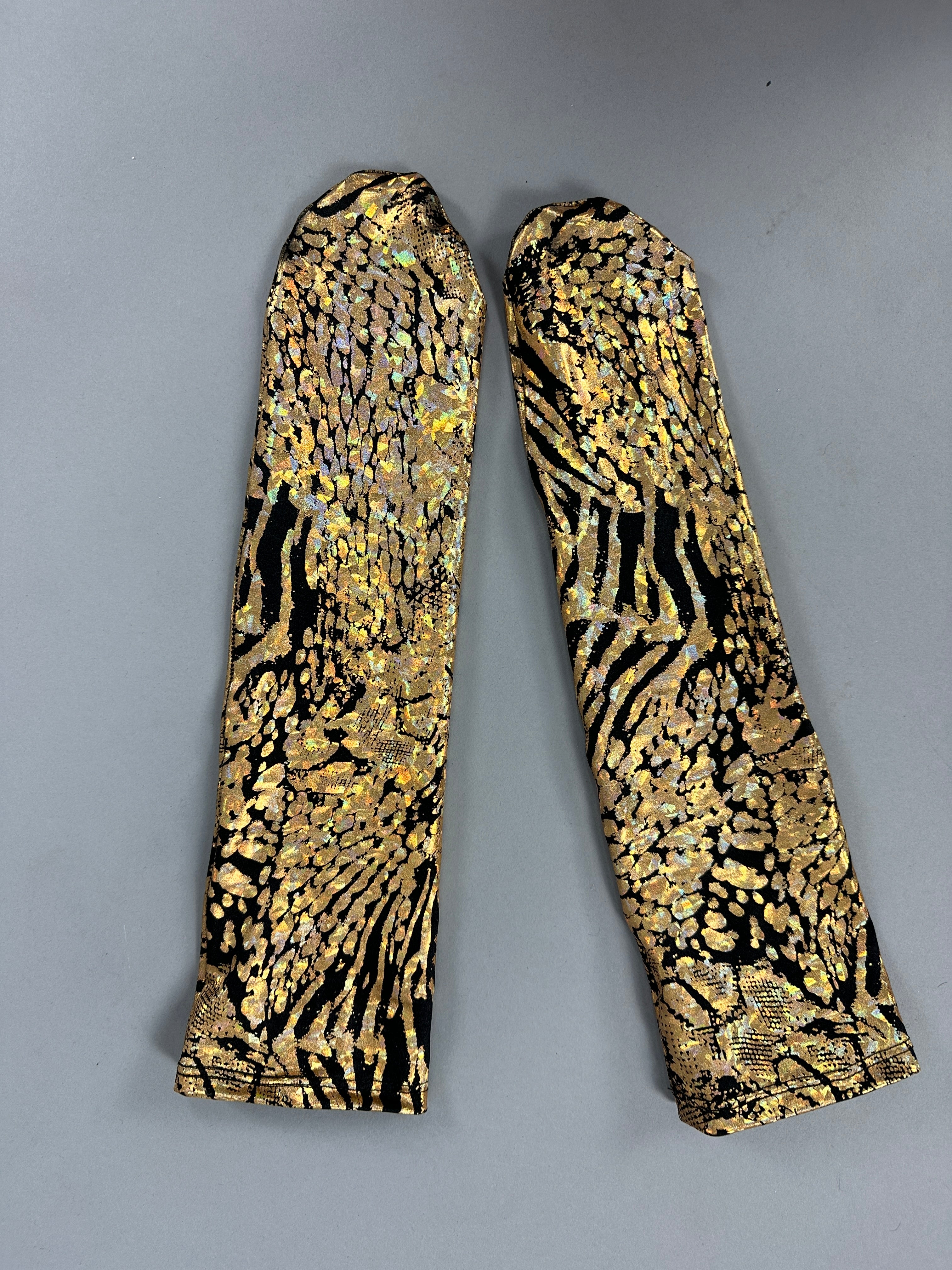 Two socks with a gold and black abstract pattern on a gray background capture the elegance of the Gold & Black Gazelle creature costume.
