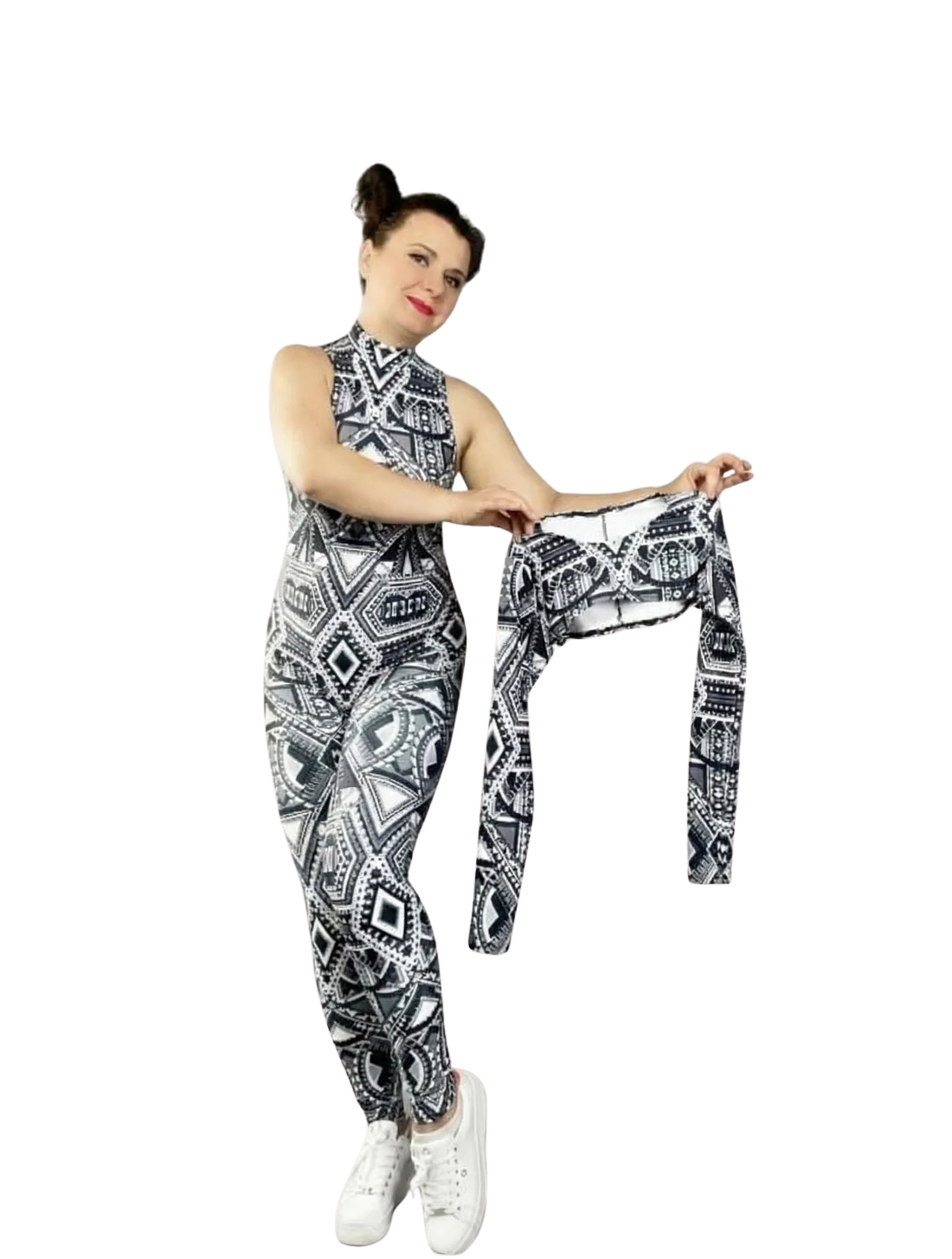 A woman wears the Geometric Catsuit with halter neck and UV-reactive tribal print, holding a matching long-sleeved crop top. The vibrant patterns create a striking glow under blacklight against a white background.