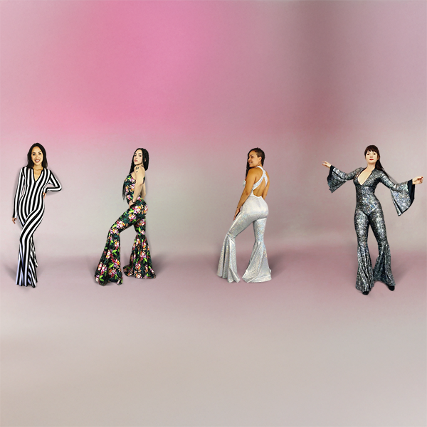 Four women stand apart wearing colorful, retro flared jumpsuits on a gradient pink and gray background.