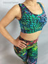 A person stands confidently, hands on hips, wearing vibrant Peacock Leggings and Top activewear adorned with a stunning peacock feather design—perfect for yoga fashion and exotic dance wear, trending now.