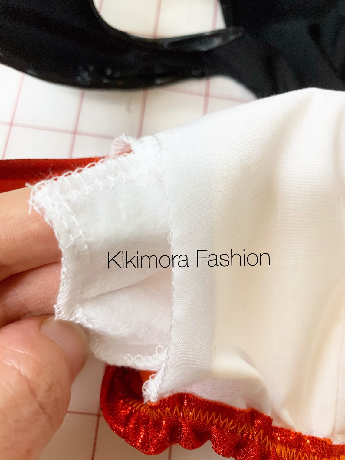 A hand holds a white Elf Ears Face Mask with red trim, text reads "Kikimora Fashion," showcasing handcrafted, reusable Baby Yoda costume masks for all ages.