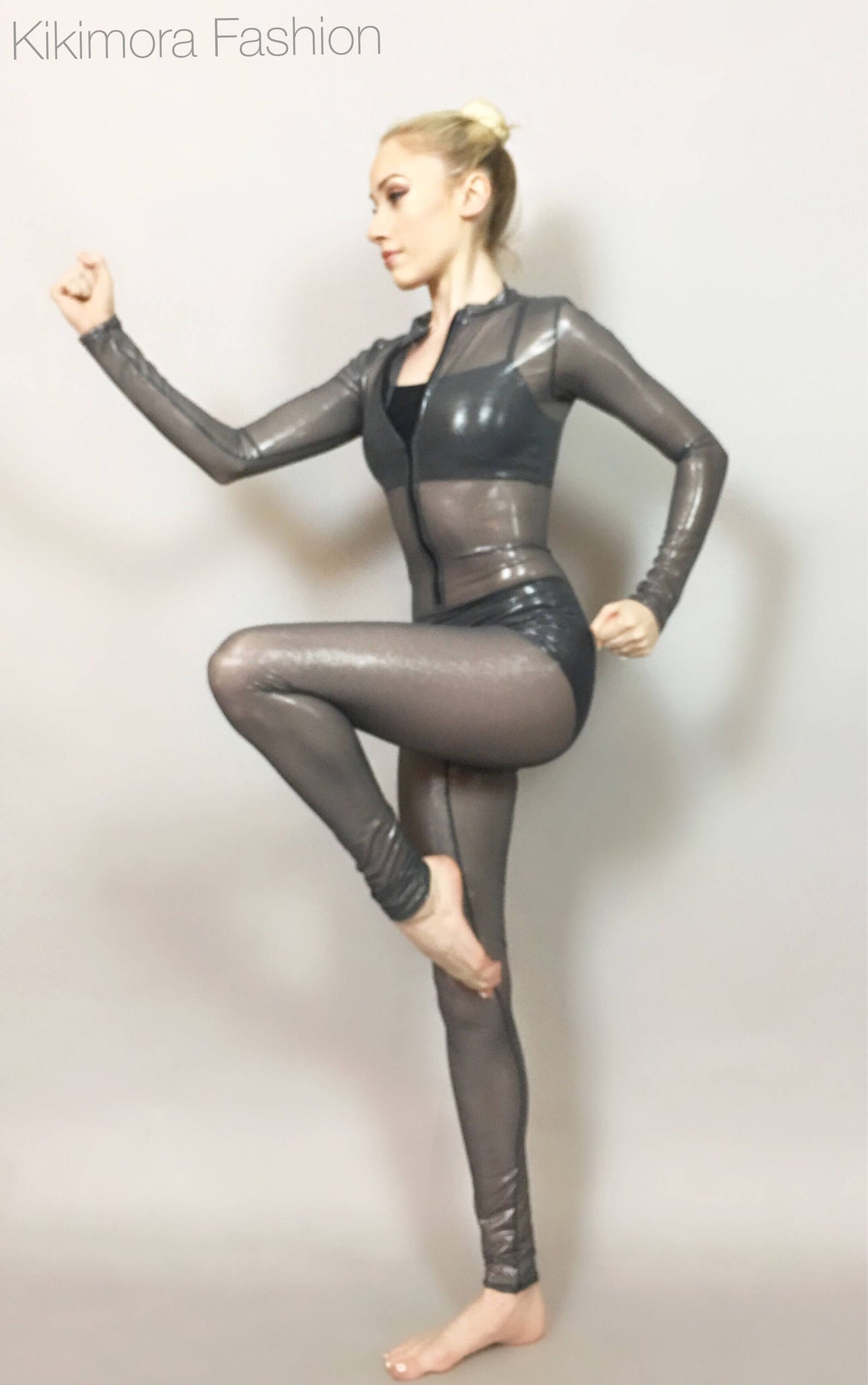 A person poses in a Metallic Gray Catsuit, featuring a crew neck and full sleeves, with one leg raised against a plain backdrop.