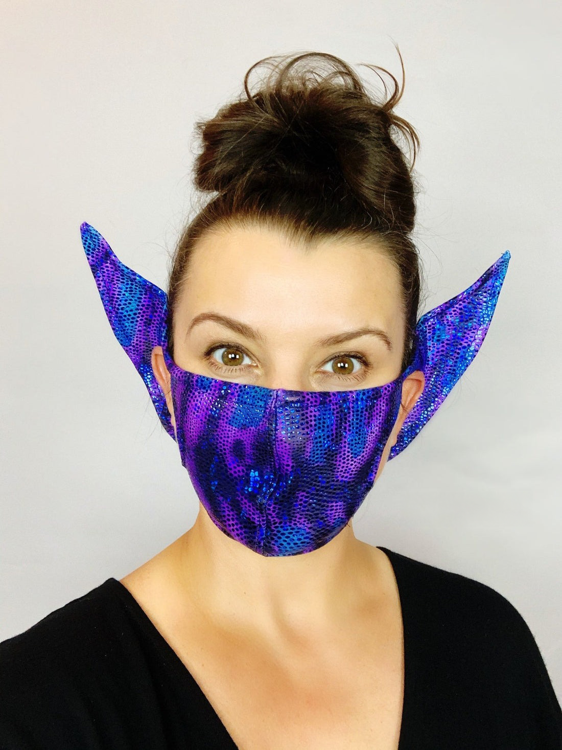 Woman smiles at the camera wearing the Elf Ears Face Mask for All Ages—a reusable Mandalorian Baby Yoda mask that&
