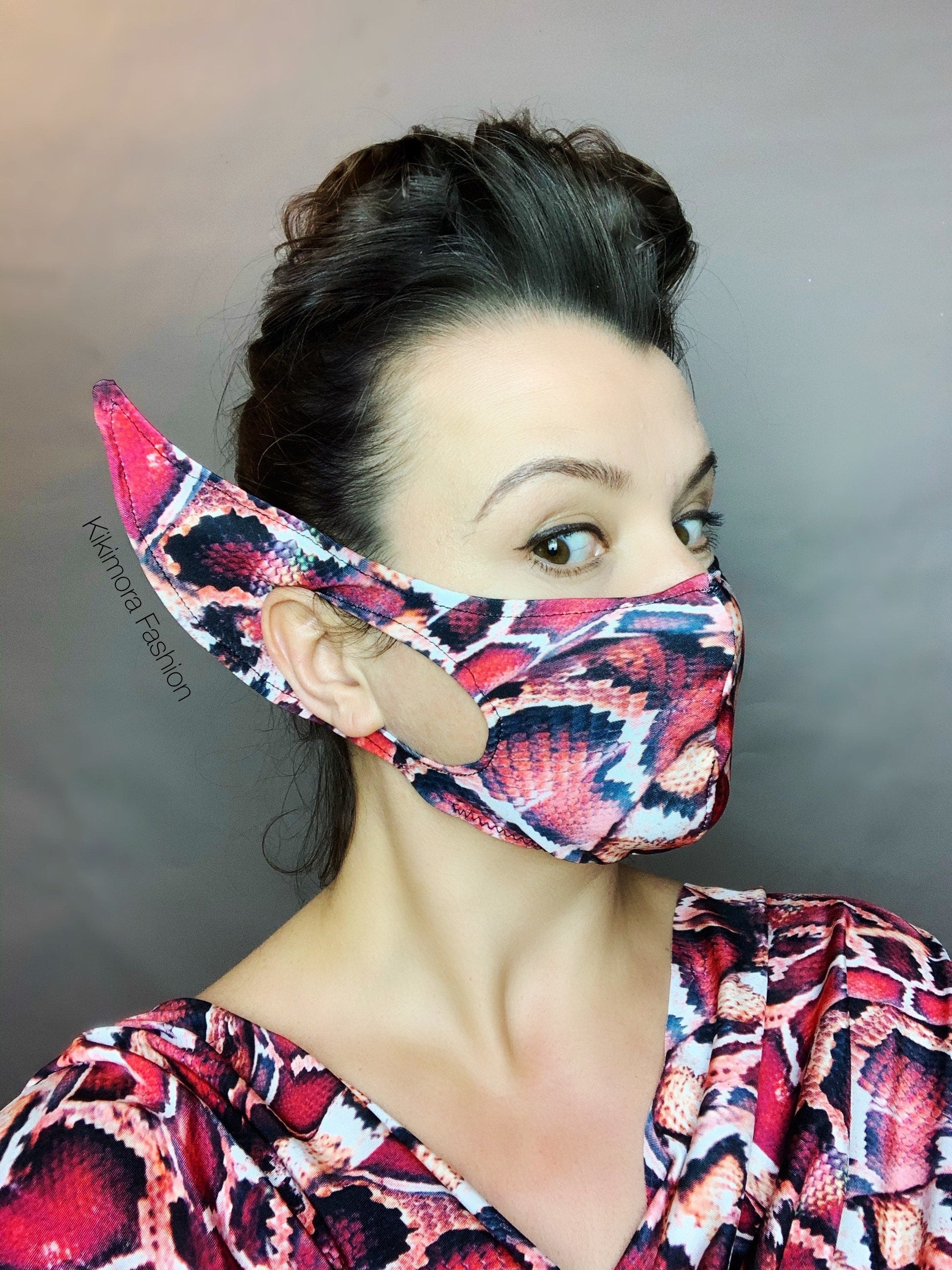 Woman wearing the Elf Ears Face Mask for All Ages, a reusable elf mask with a snake print inspired by Mandalorian Baby Yoda costume, paired with her matching top against a gray background.