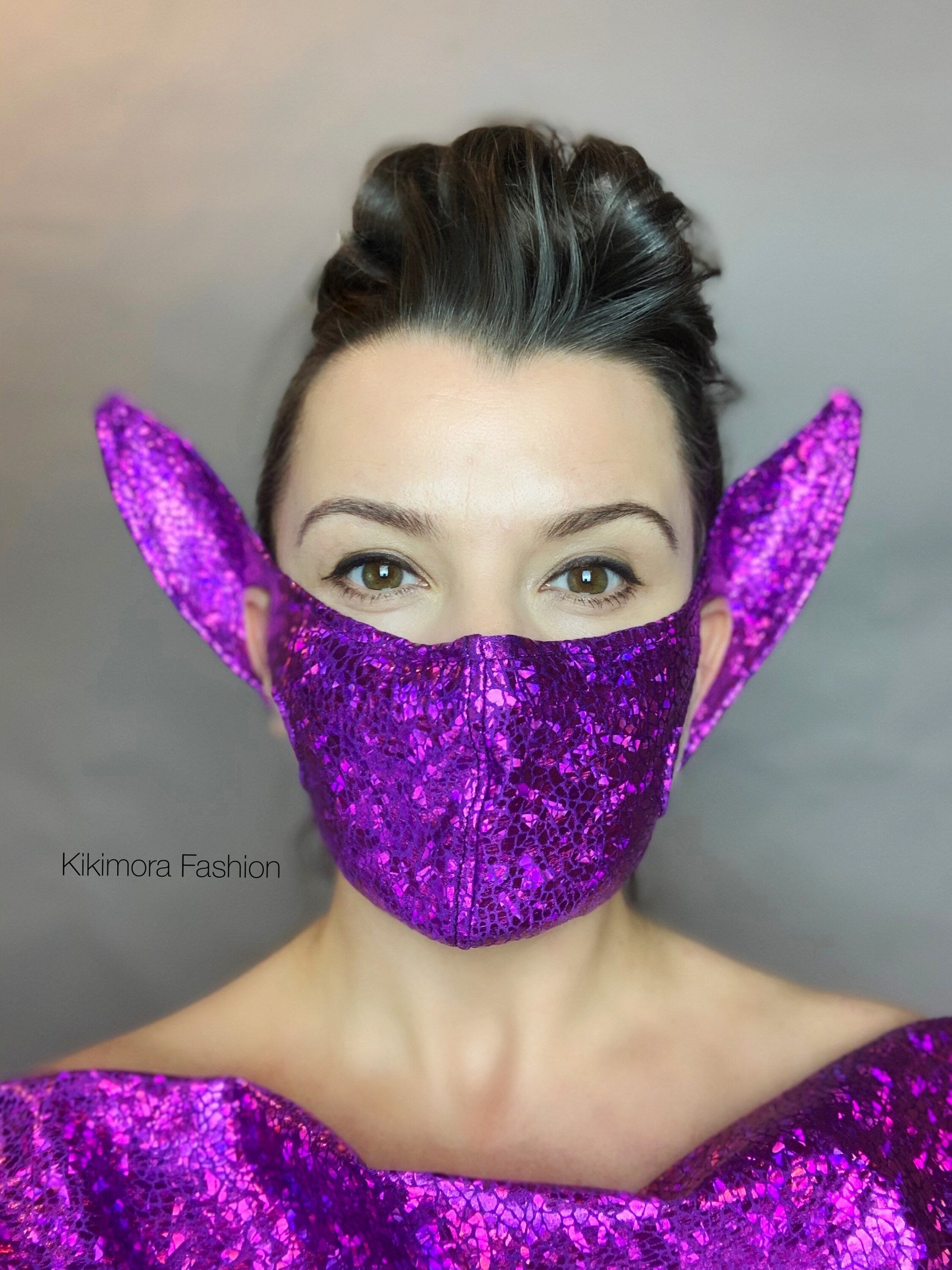 Person wears the Elf Ears Face Mask for All Ages, a reusable elf mask inspired by Mandalorian Baby Yoda, paired with beautiful futuristic clothing featuring pointed ear-like extensions, set against a gray background.