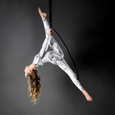 Wearing a Face Mask, Elf Ears Cosplay Costume Accessory, the aerial artist performs a split pose on a suspended hoop in front of a dark backdrop.