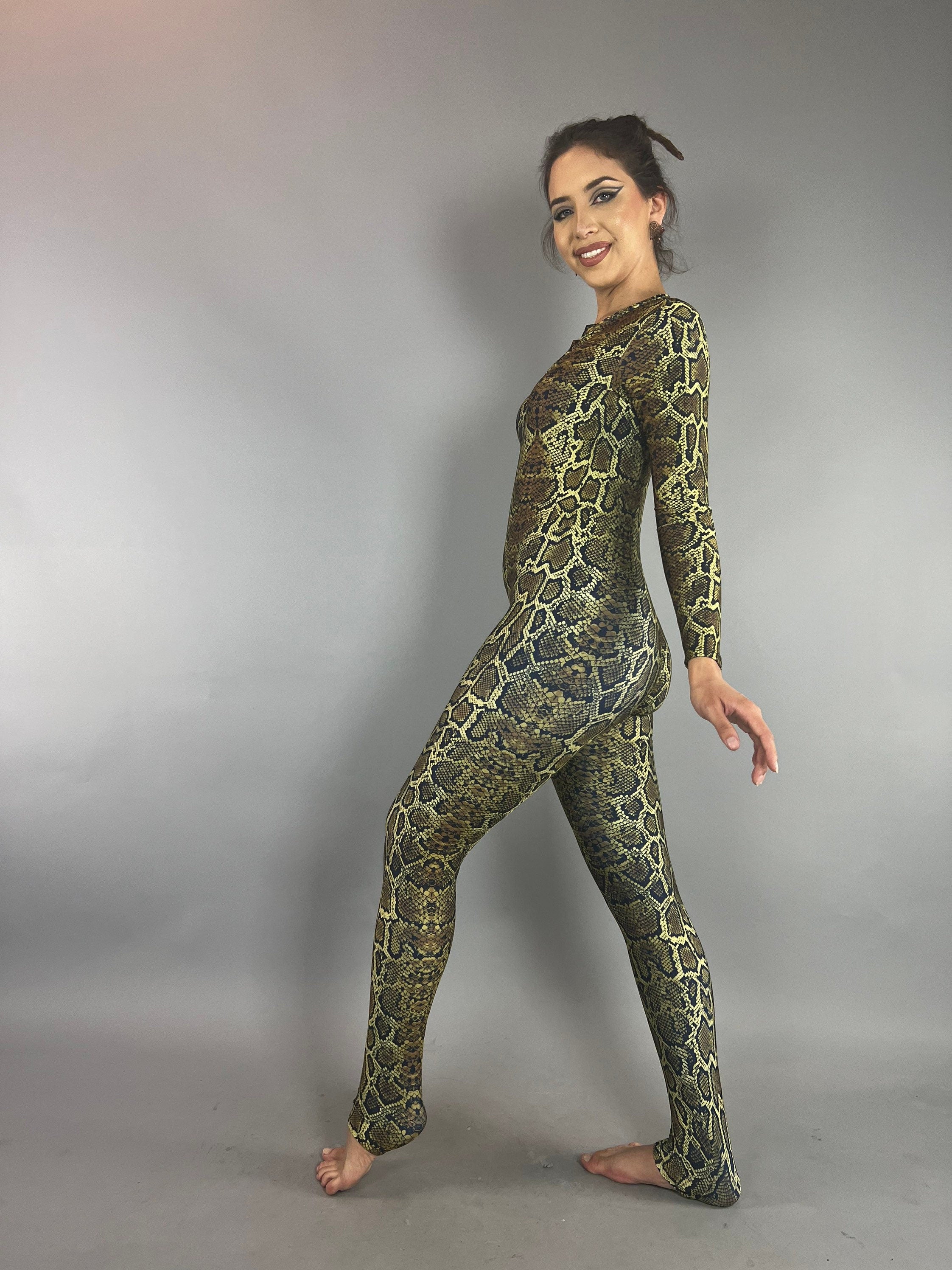 Barefoot woman smiles in the Beautiful Snake Catsuit, a UV protective and trending festival fashion piece that’s also ideal for watersports, yoga, and swimsuits; posed against a plain gray background.