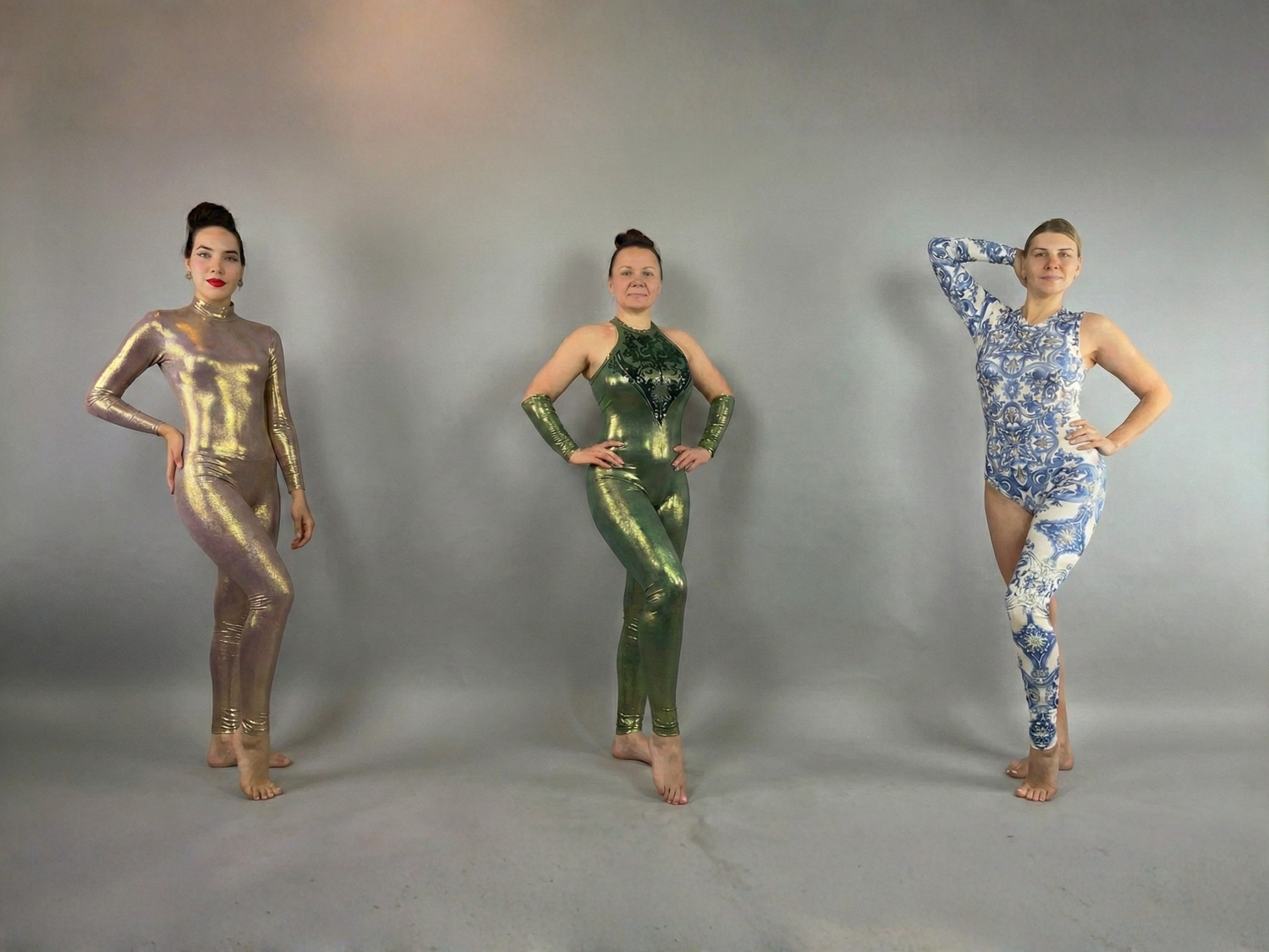 Three women in patterned bodysuits pose barefoot against a plain gray background.