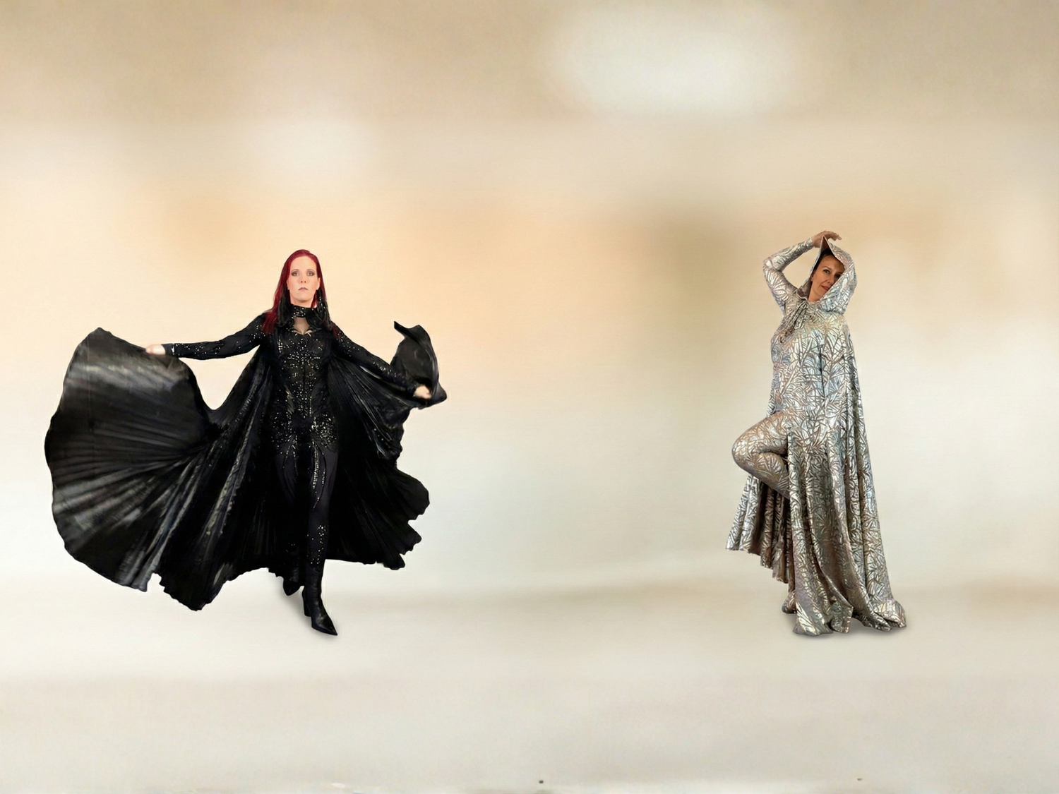 Two people pose in dramatic, shiny costumes—one in flowing black, the other in sparkling silver.