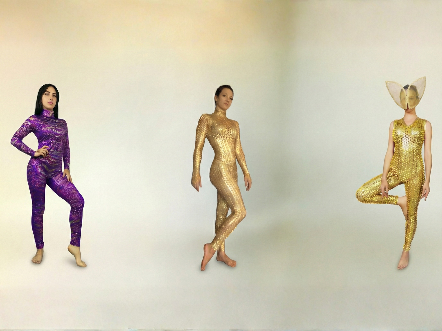 Three people in colorful, textured bodysuits pose against a plain background; one wears a mask with large ears.