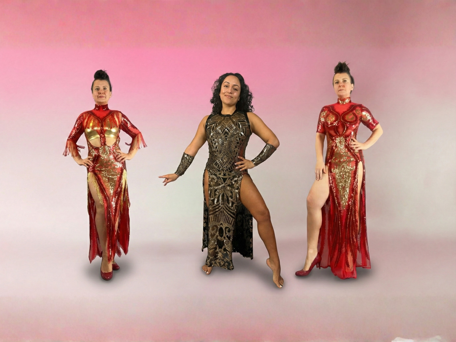 Three women in ornate, high-slit dresses posing confidently against a pink and white gradient background.
