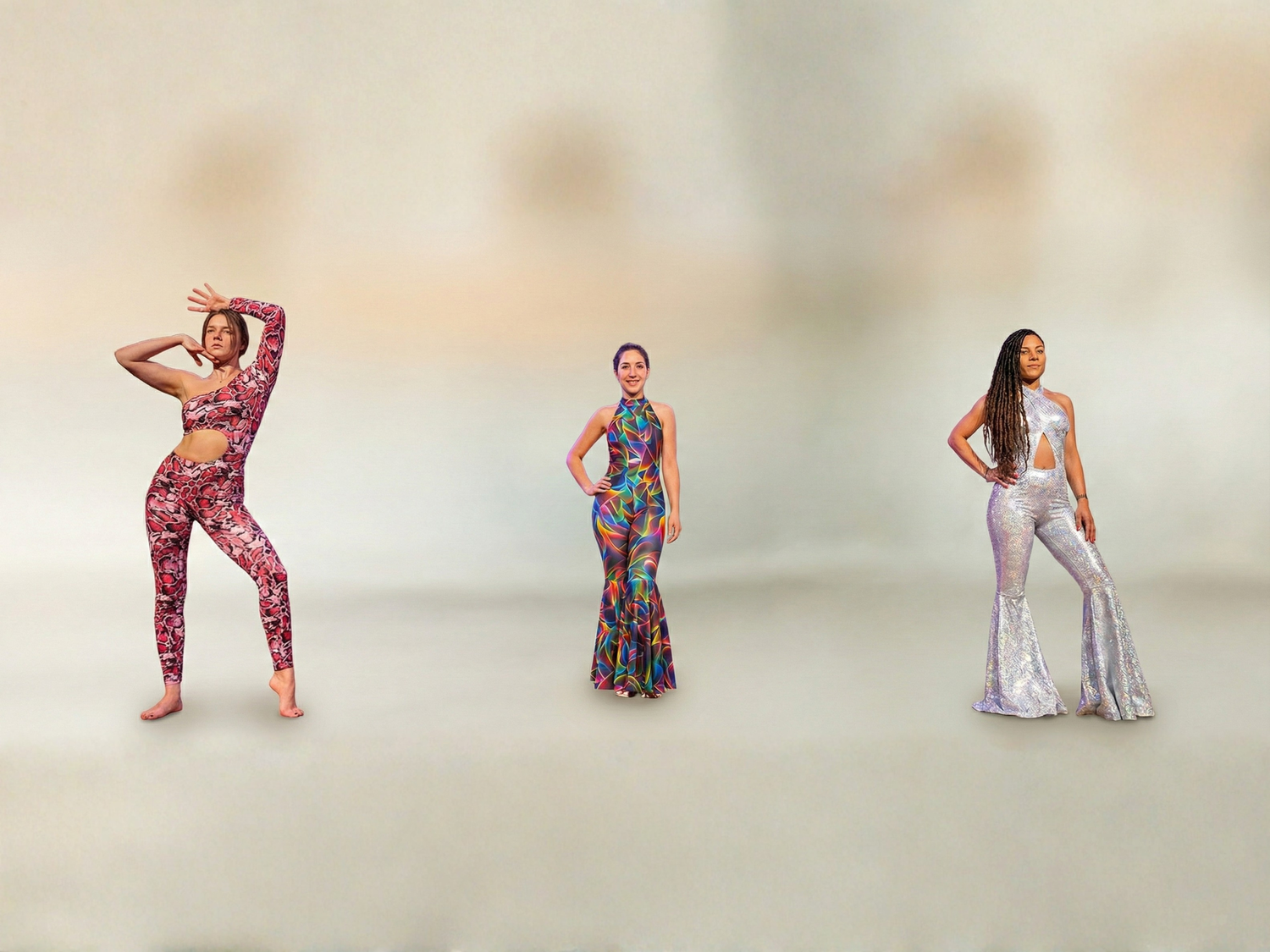 Three women pose in colorful, patterned jumpsuits against a plain, neutral background.