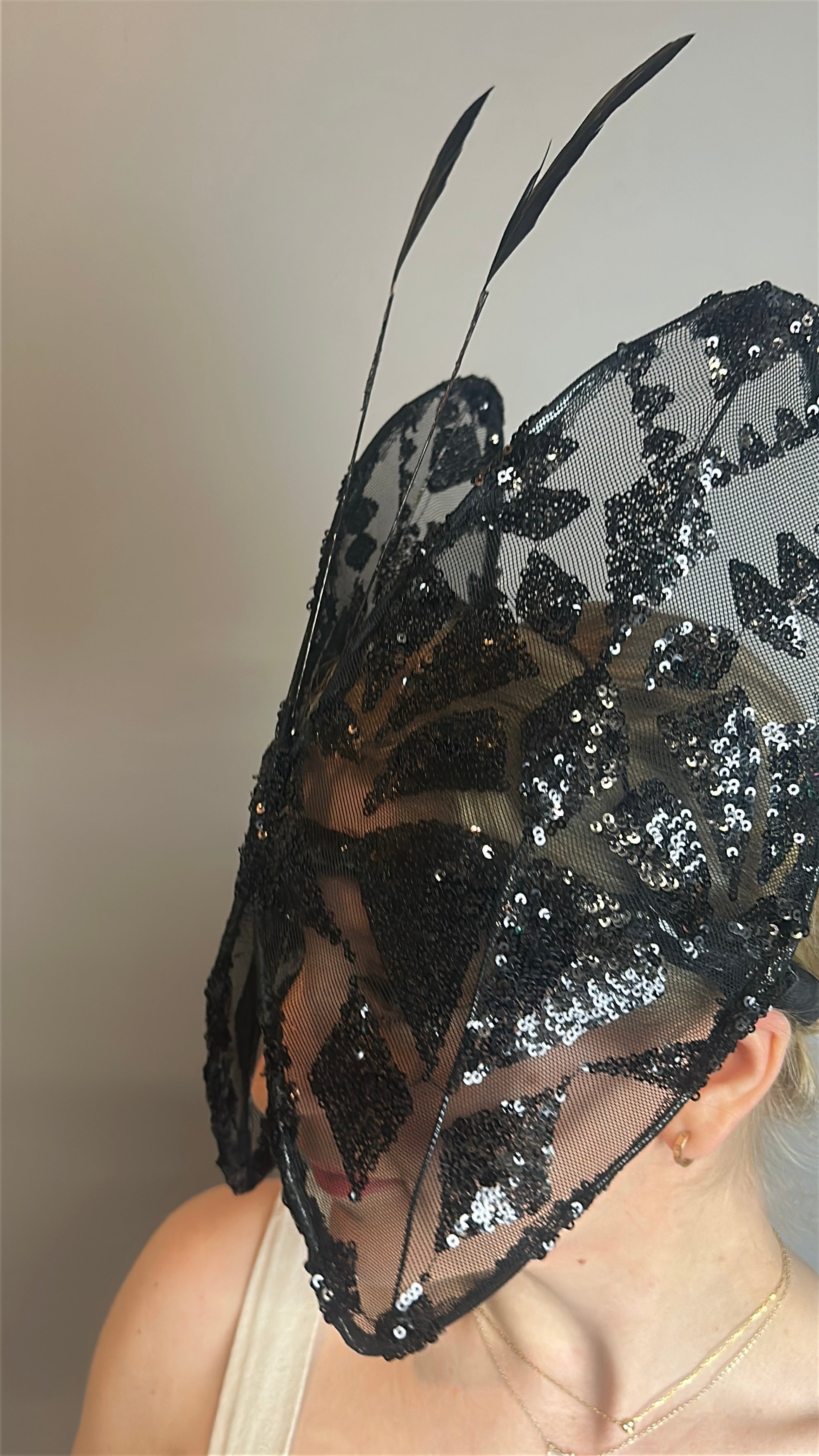Person wearing the Butterfly Headpiece—an open face black lace hat—shown from the side, paired with a festive holiday costume accessory, for a unique and eye-catching look.