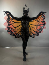 Model wearing the Black Sequin Full Costume Butterfly, which features striking orange and black wings and antennae, poses against a plain background—an eye-catching piece of wearable art.