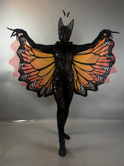 Model wearing the Black Sequin Full Costume Butterfly, which features striking orange and black wings and antennae, poses against a plain background—an eye-catching piece of wearable art.