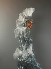 A person smiles, wearing the Sea Creature costume with shimmering, fin-like details against a plain background, showcasing its couture-inspired design.