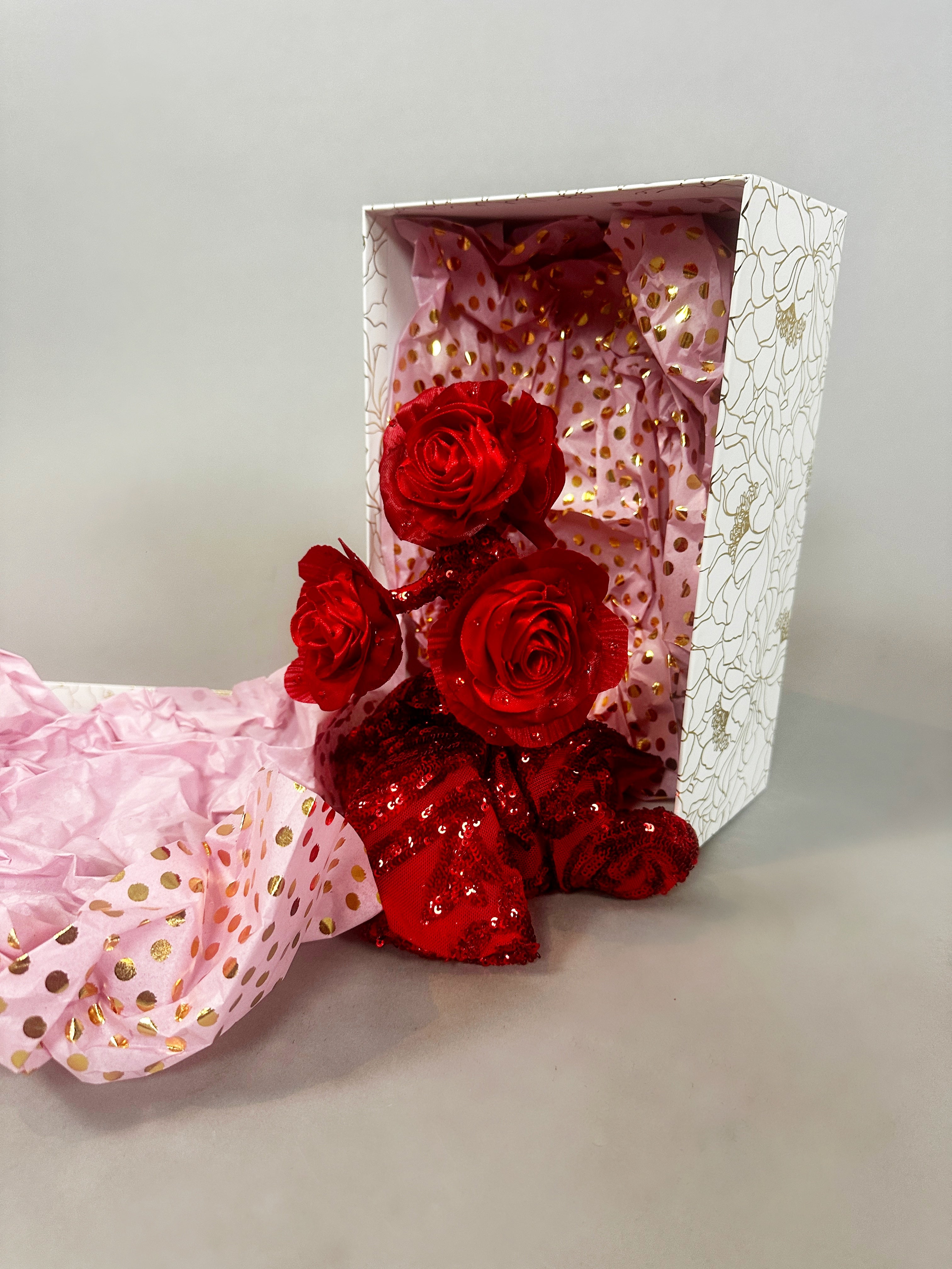 Three Mini Living Rose doll ornaments and red sequined fabric, arranged in a white gift box with pink and gold tissue paper, create a magical art object inspired by Kikimora Studio.