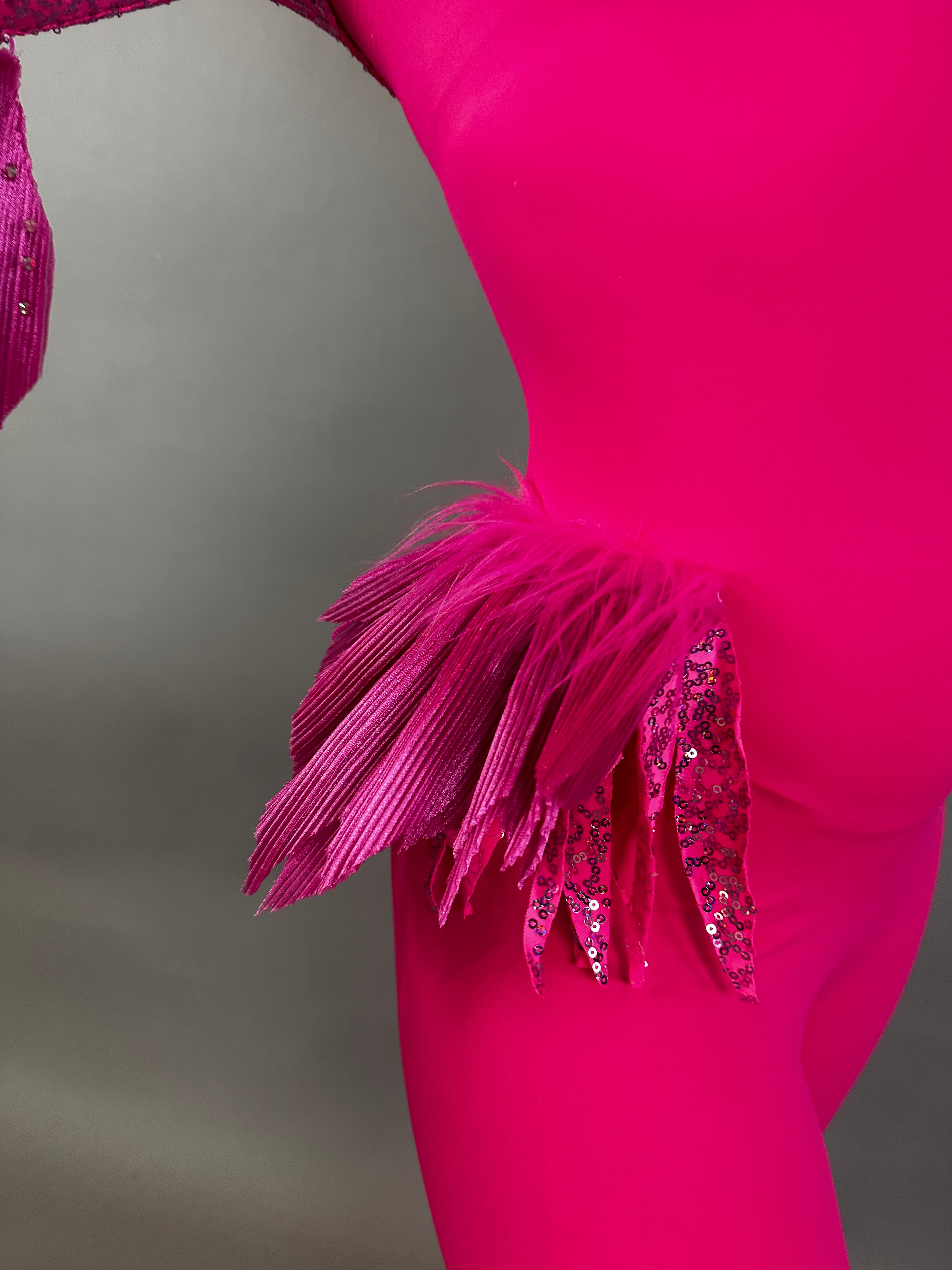 Model wearing the Pink Bird Full Costume for aerial and dancers, featuring pleated and sequined feather-like hip details, shown against a plain background.