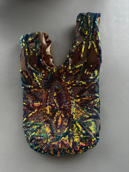 Handcrafted reversible sequin mini tote with multicolored sequins and brown lining, laying flat on a gray surface—a sustainable fashion accessory that’s eye-catching and upcycled.