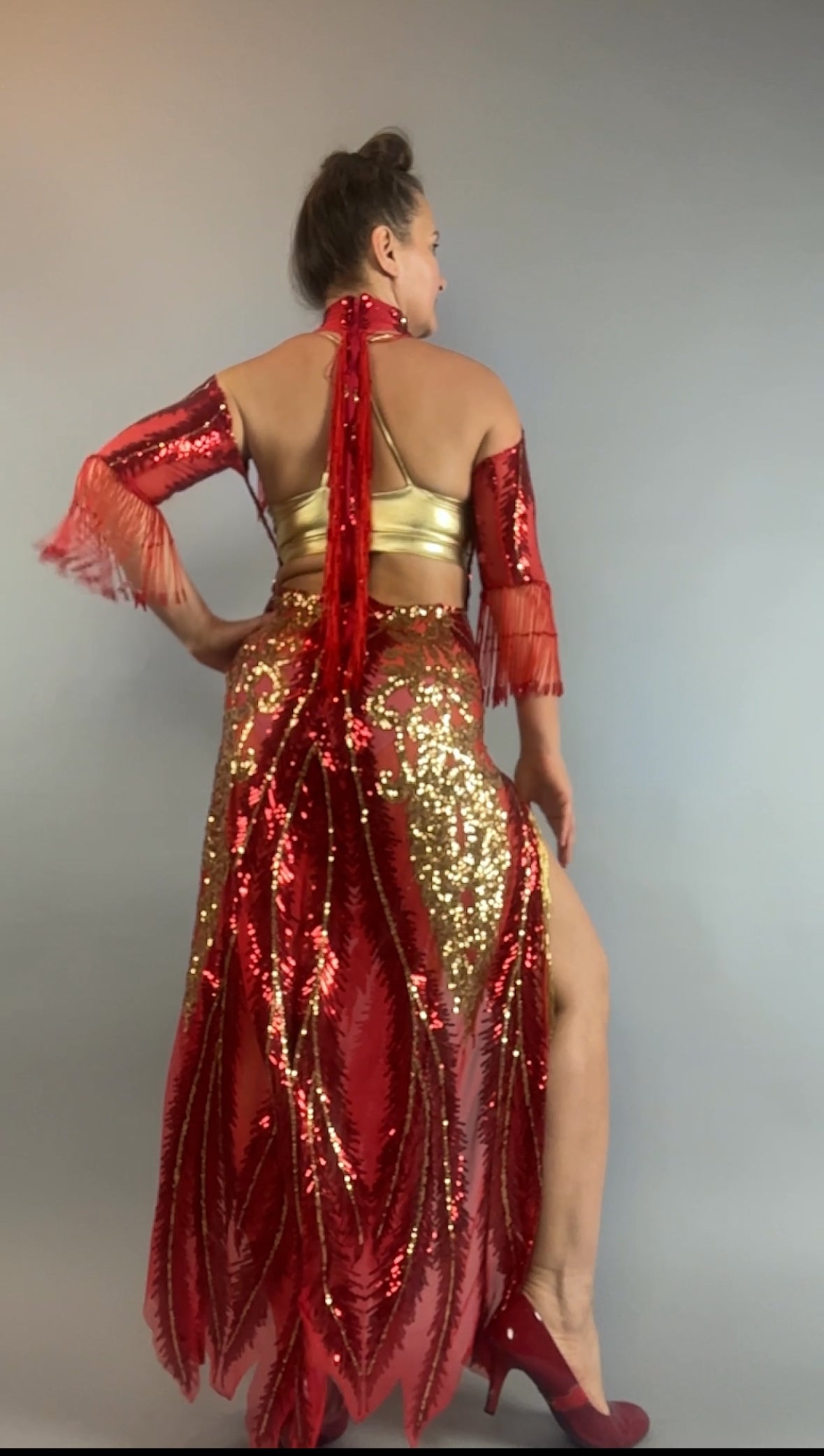 A person poses with their back facing in the bearded French accessories Sequin Sheer Dress, featuring a backless design and beaded fringe accessories.