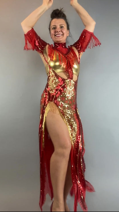 Woman smiles, posing with arms raised and one leg lifted in a bearded French accessories Sequin Sheer Dress—backless with a thigh-high slit—styled with beaded fringe accessories.