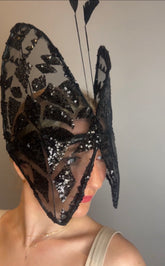 Woman wearing a Butterfly Headpiece—black lace hat and festive holiday costume accessory—in an open-face style, partially covering her face.
