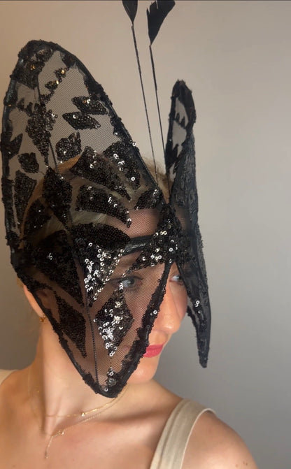 Woman wearing a Butterfly Headpiece—black lace hat and festive holiday costume accessory—in an open-face style, partially covering her face.