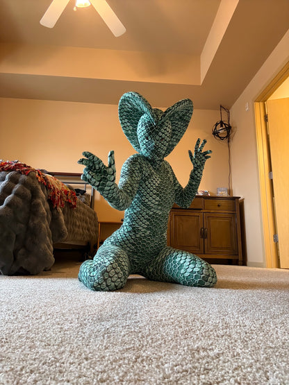 Person kneeling on carpet wears the Green pixel Cobra Costume, featuring a snake print catsuit and large headdress—perfect for serpent cosplay, dance, or contortionist acts.