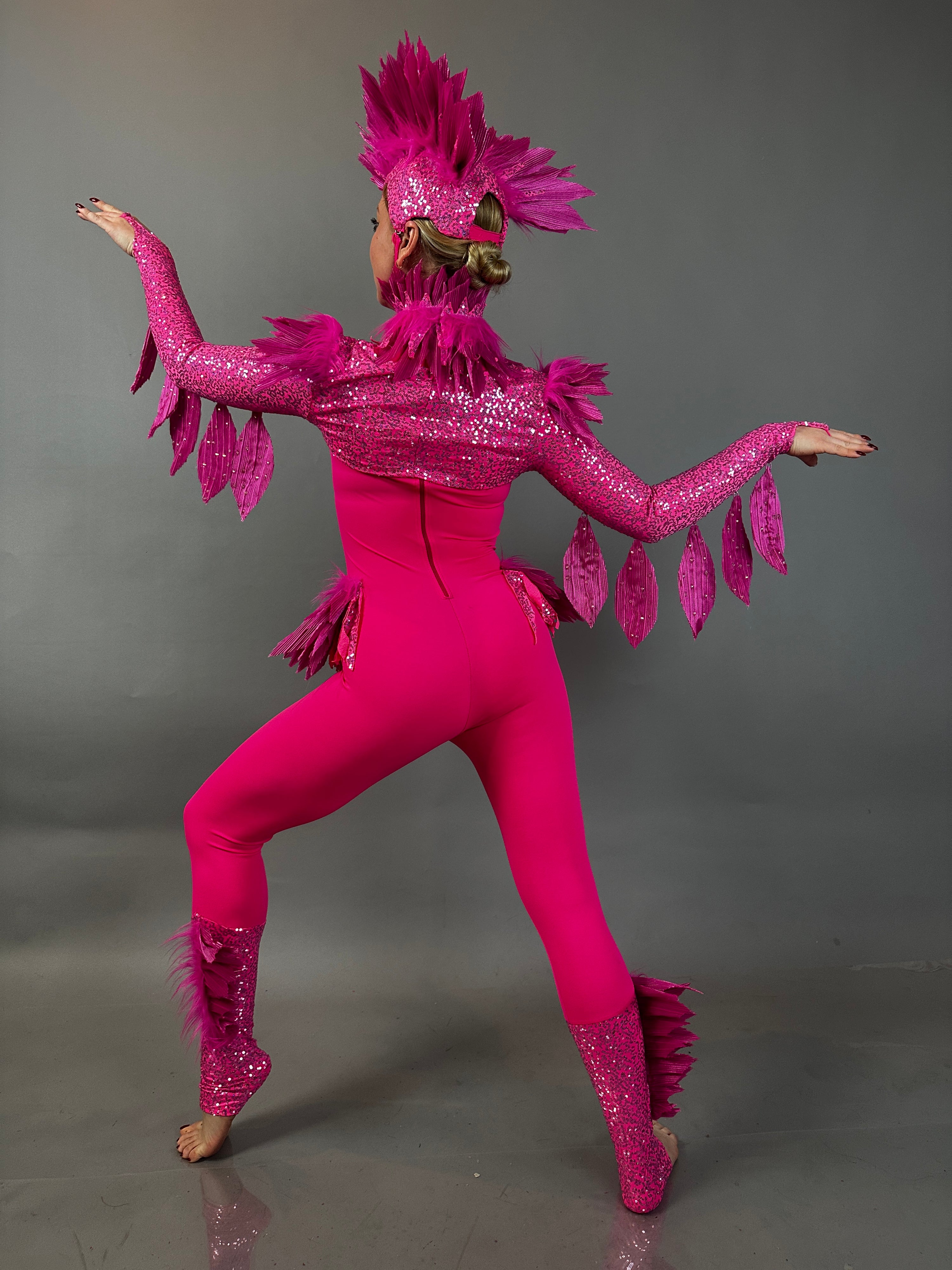 A performer in the Pink bird full costume for aerial and dancers poses with arms raised against a gray background, showcasing the energetic style of this stage-ready outfit.